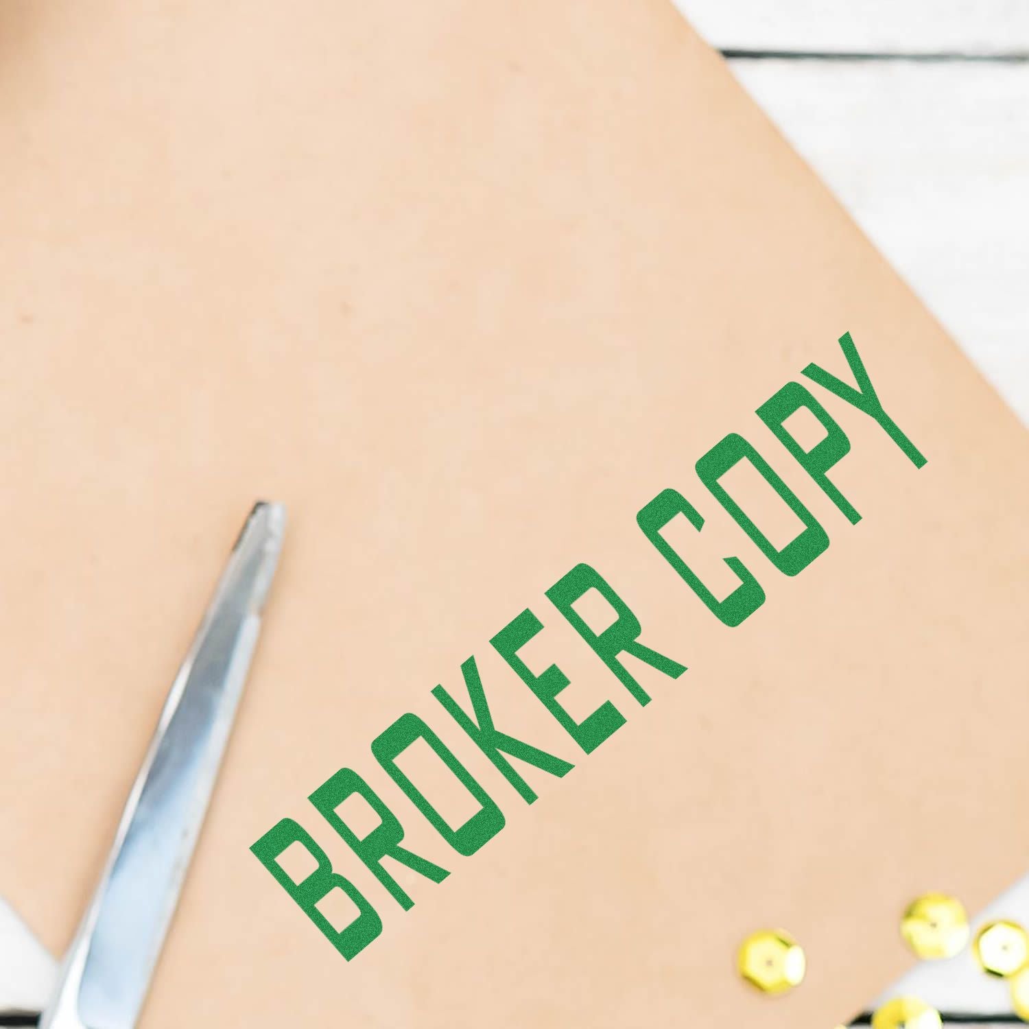 Slim Pre-Inked Broker Copy Stamp in green ink on a brown envelope, with scissors and gold sequins nearby.