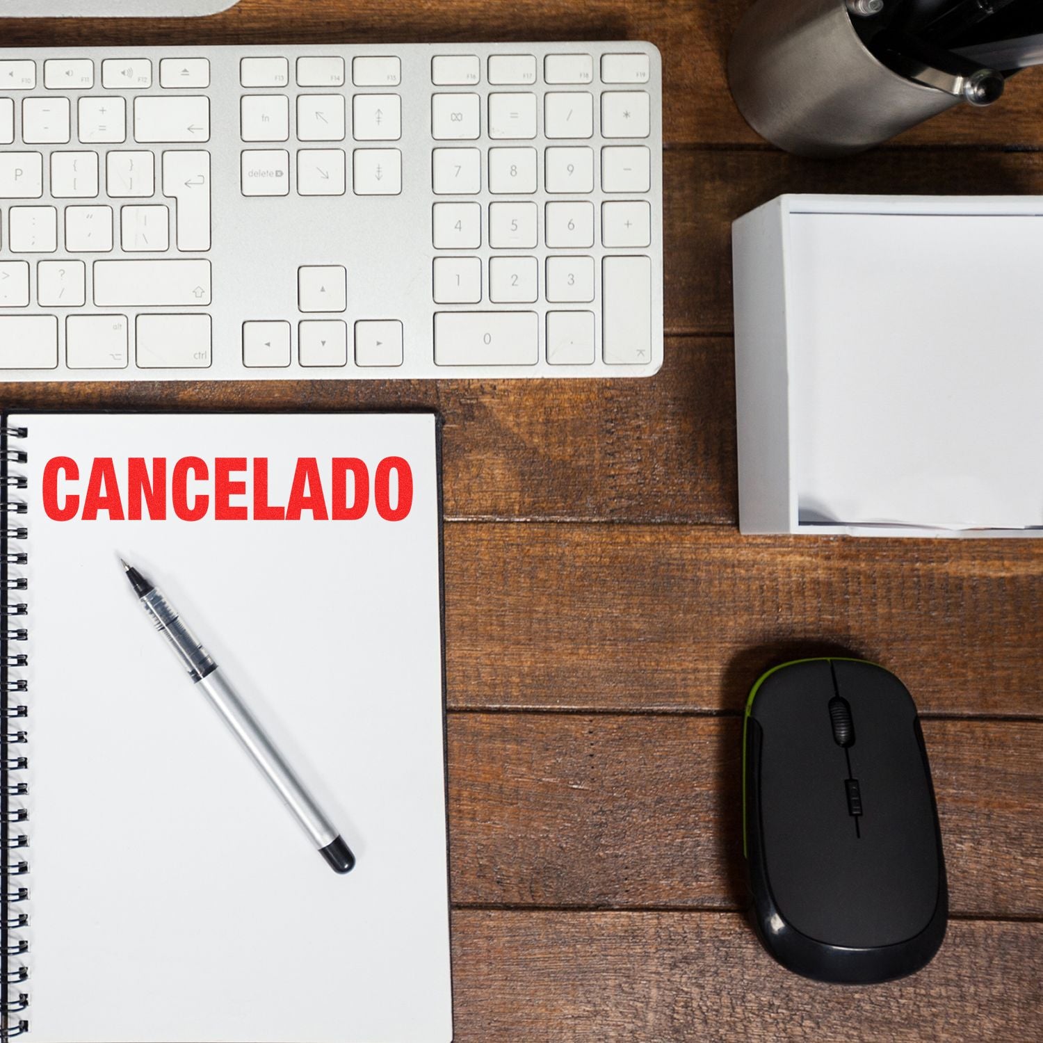 Self Inking Cancelado Stamp used on a notebook, placed on a wooden desk with a keyboard, mouse, pen, and office supplies.