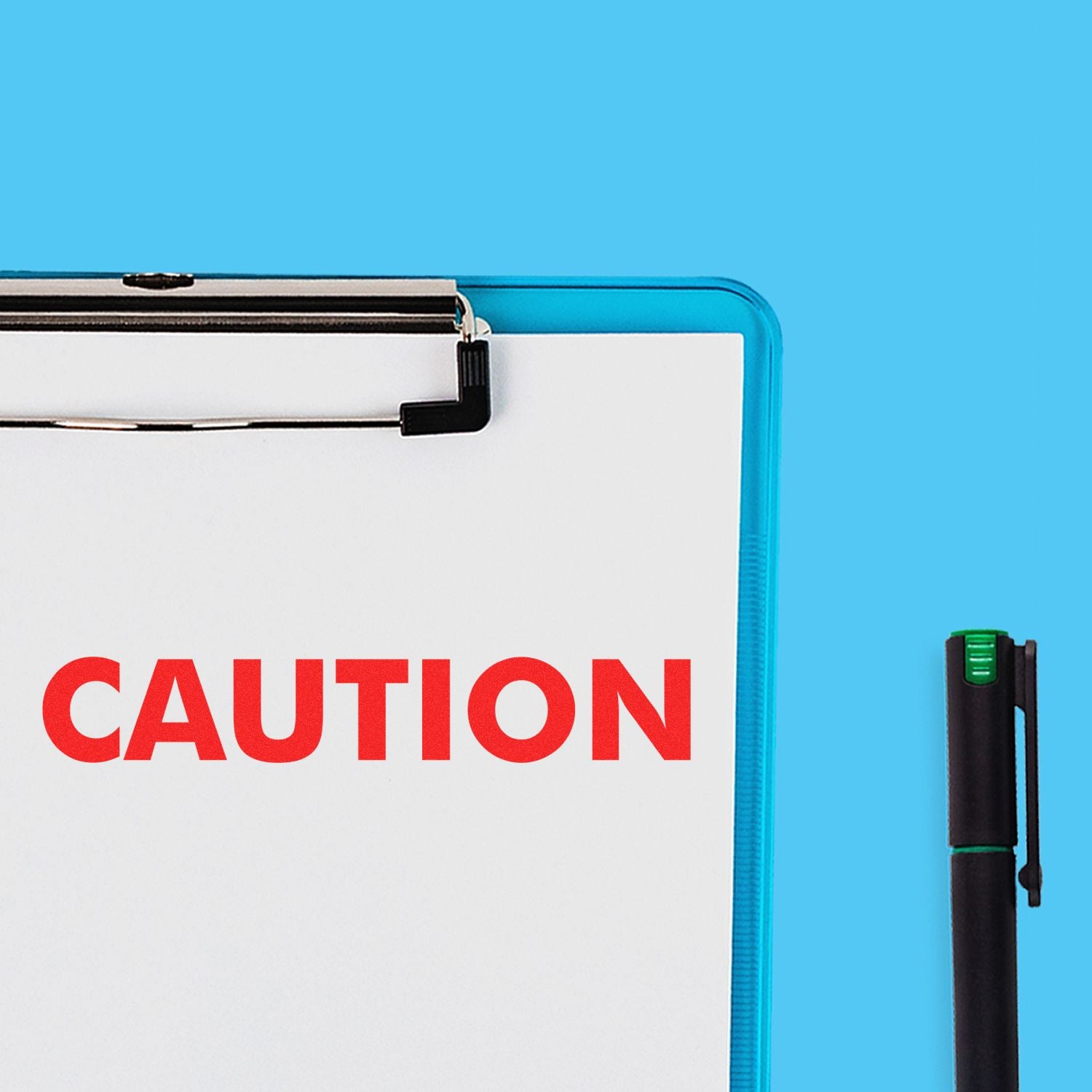 Large Caution Rubber Stamp in red ink on a white paper clipped to a blue clipboard, with a black pen beside it on a blue background.