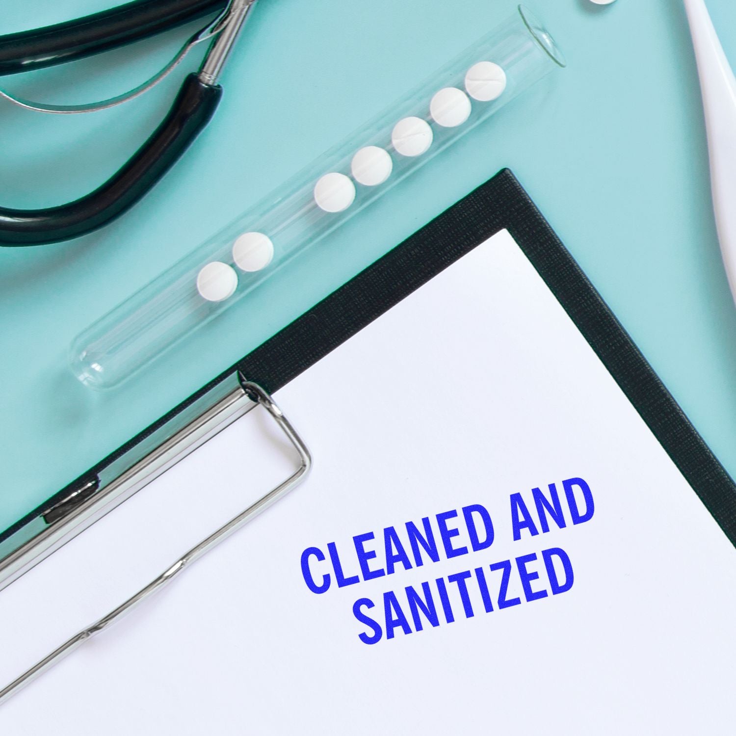 Clipboard stamped with CLEANED AND SANITIZED using the Large Pre-Inked Cleaned and Sanitized Stamp, next to medical tools on a blue surface.