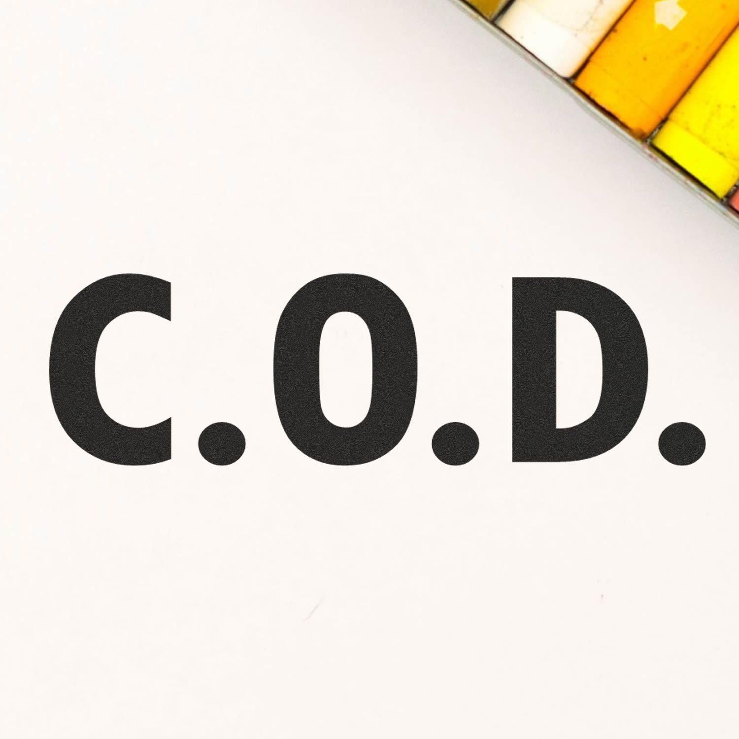 Large Self Inking COD Office Stamp imprinting 'C.O.D.' on white paper, with a glimpse of colored pencils in the background.