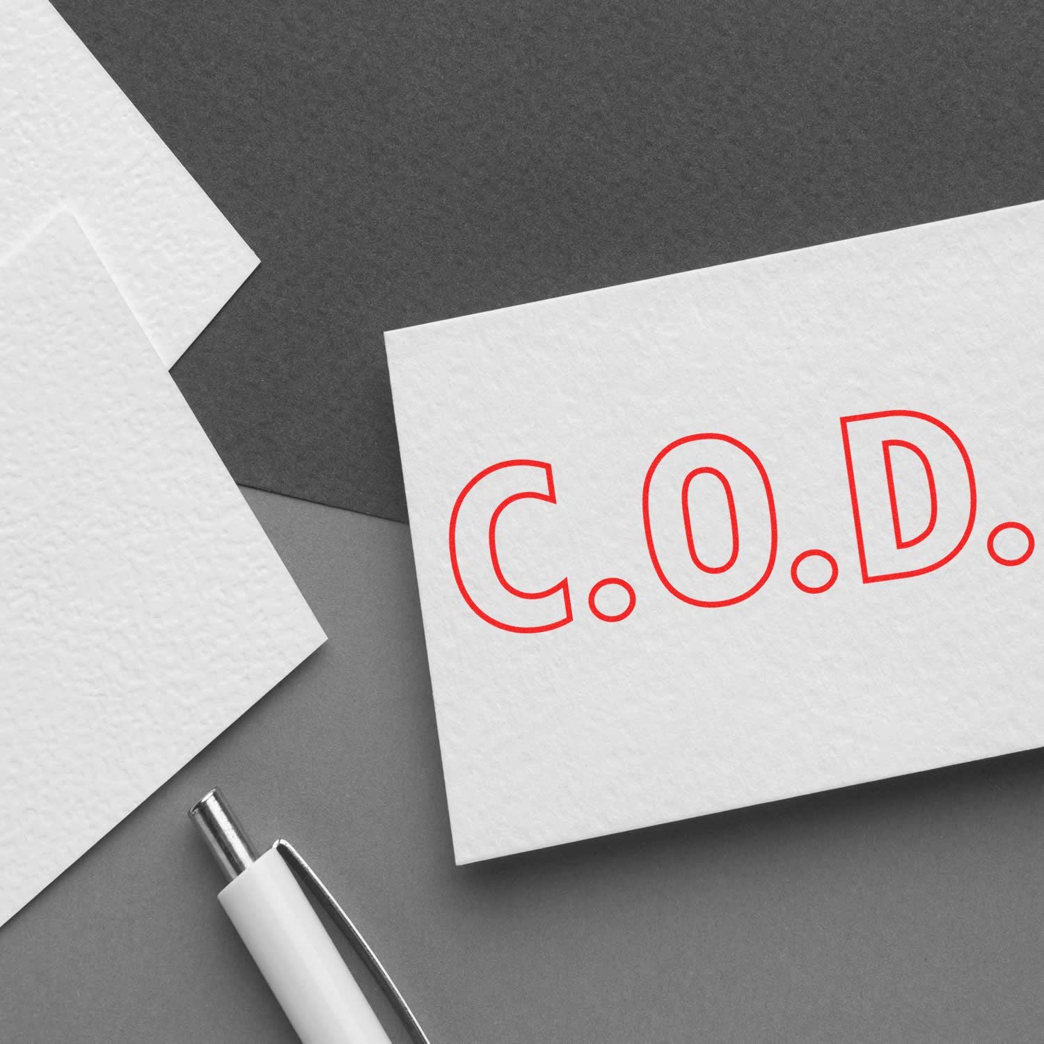 Slim Pre-Inked COD Stamp With Outline Text in red on a white card, placed on a gray surface with a pen and papers nearby.