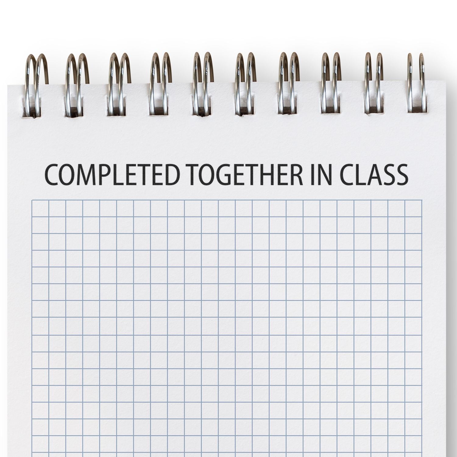 A notebook with a grid pattern and the text COMPLETED TOGETHER IN CLASS stamped on it using the Large Self Inking Completed Together Stamp.