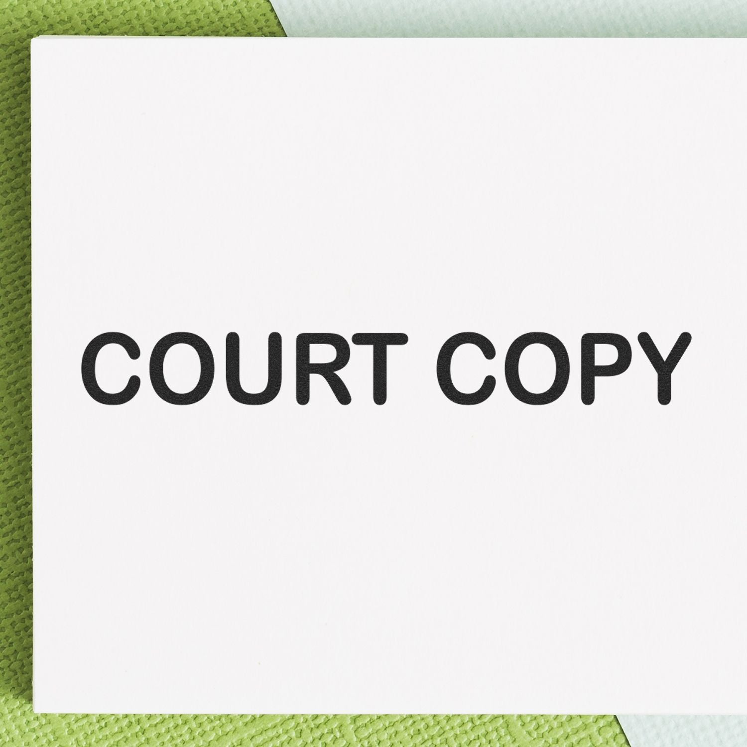 Large Self Inking Court Copy Stamp imprinting COURT COPY in bold black letters on a white paper, placed on a green textured surface.