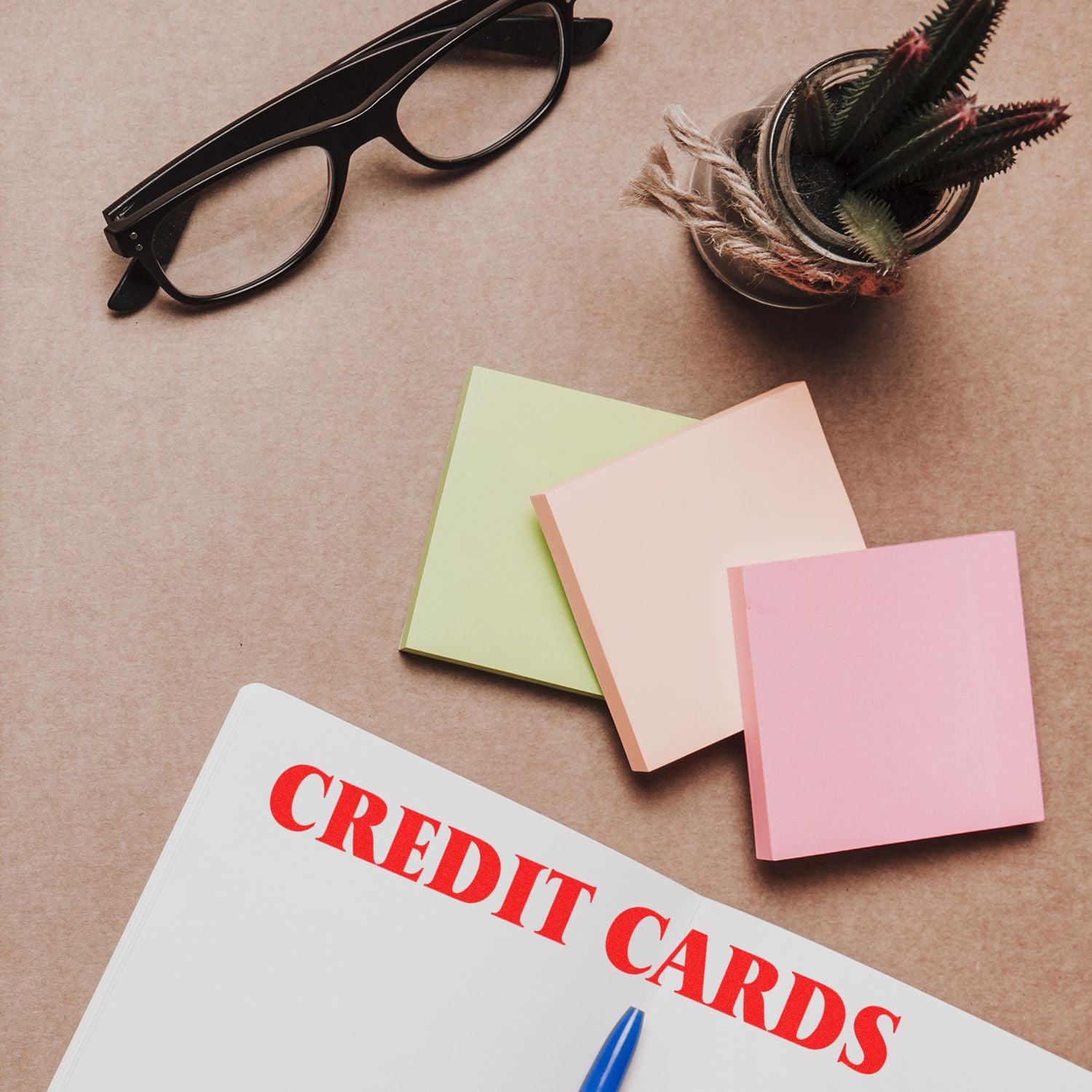 Large Self Inking Credit Cards Stamp on a desk with glasses, sticky notes, a plant, and a notebook labeled CREDIT CARDS.