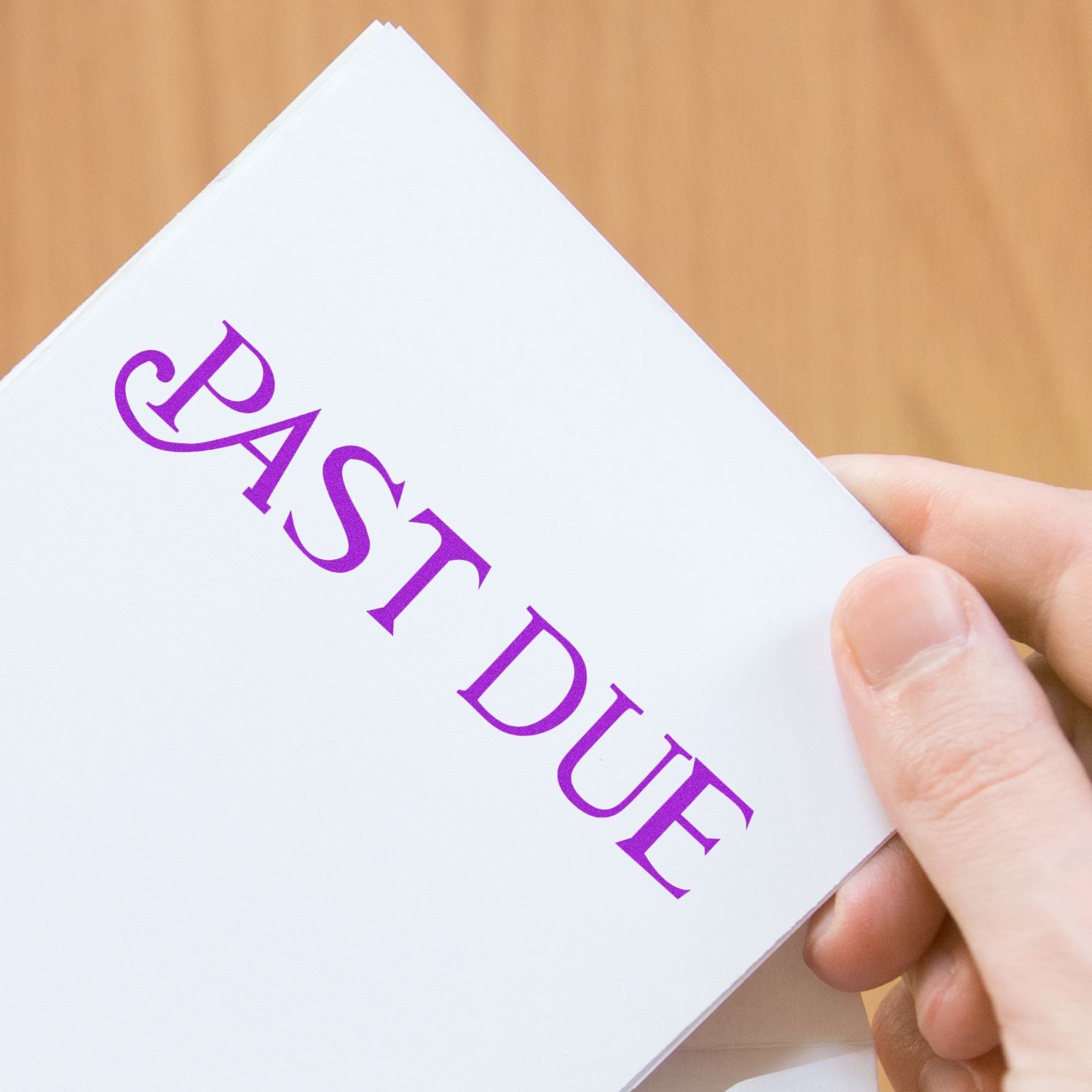 A hand holding a stamped paper with PAST DUE in purple ink, using the Self Inking Curley Past Due Stamp.