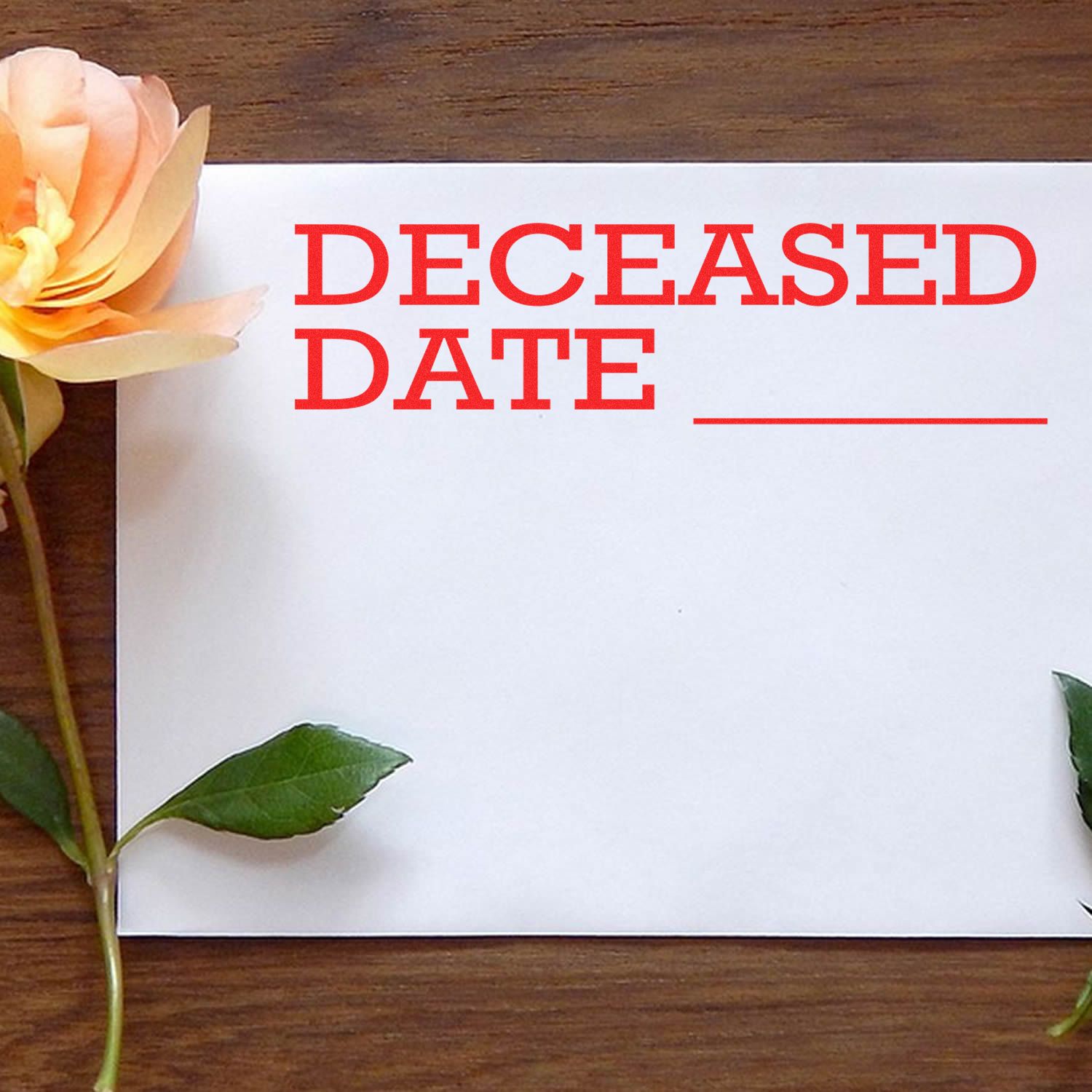 Large Deceased Date Rubber Stamp in use on a white paper with DECEASED DATE in red ink, surrounded by a yellow rose and green leaves.