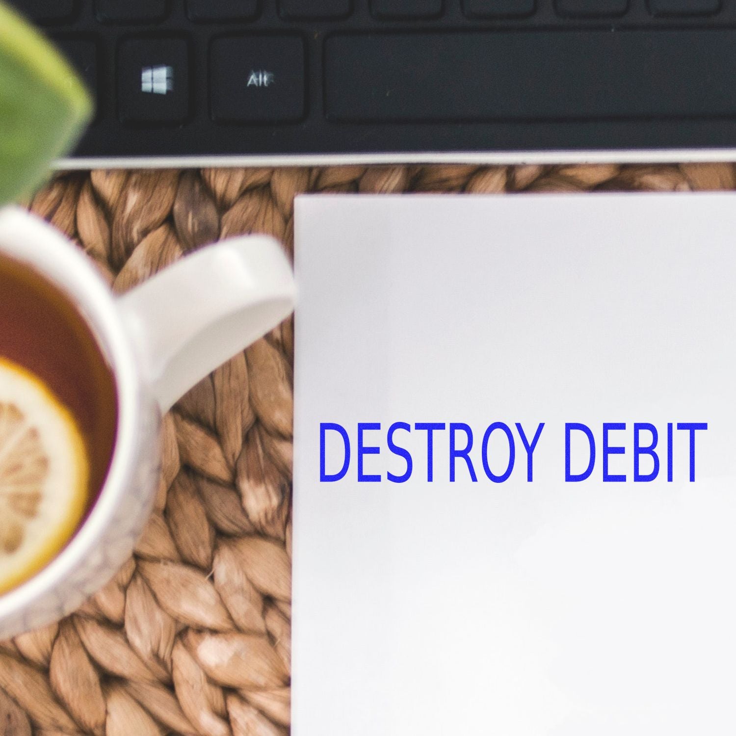 Large Destroy Debit Rubber Stamp used on a white paper next to a cup of tea with lemon and a black keyboard on a woven mat.