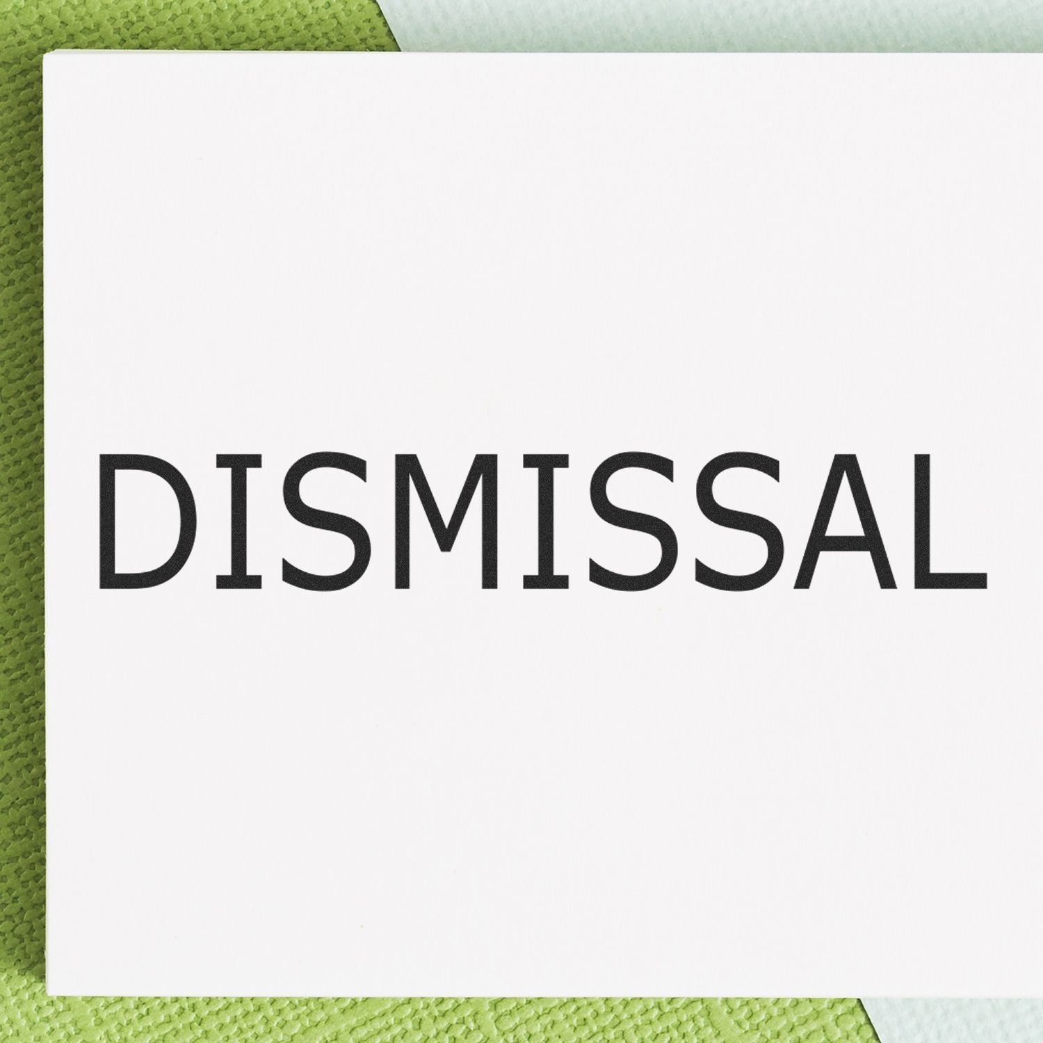 DISMISSAL Rubber Stamp in use, showing the word 'DISMISSAL' clearly stamped on a white paper background with green textured surface.