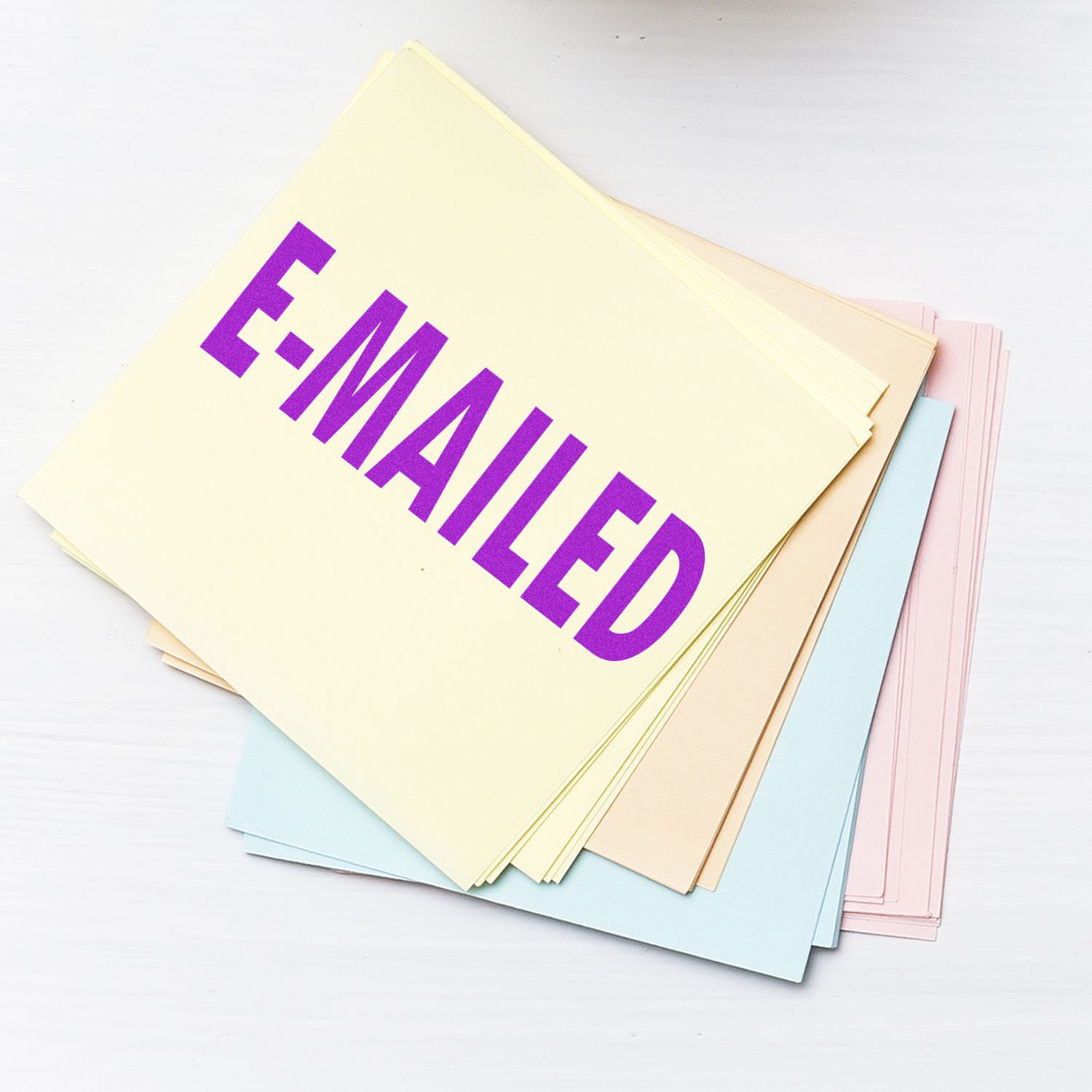 A stack of papers stamped with E-MAILED in purple ink using the Self Inking E Mailed Stamp, placed on a white surface.