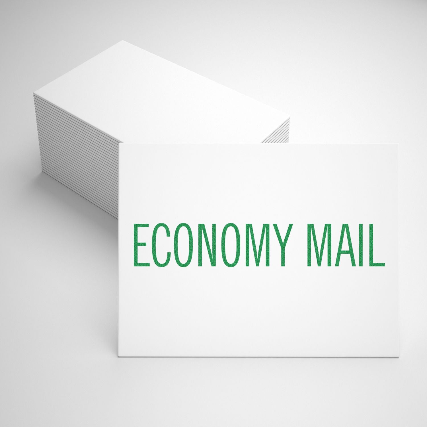 A stack of white cards stamped with ECONOMY MAIL in green using the Economy Mail Rubber Stamp, placed on a white surface.