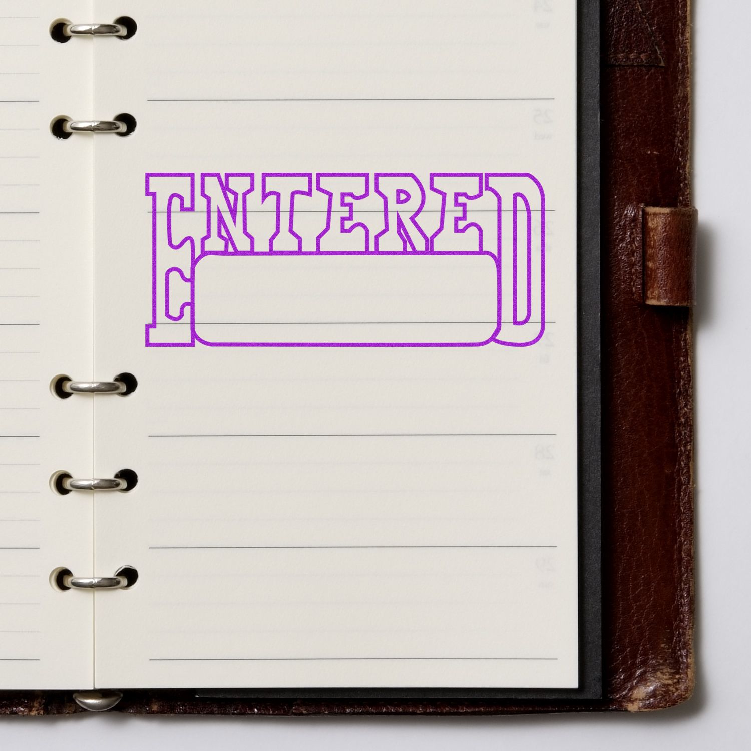 Large Pre-Inked Entered with Date Box Stamp in purple ink on an open notebook with lined pages and a brown leather cover.