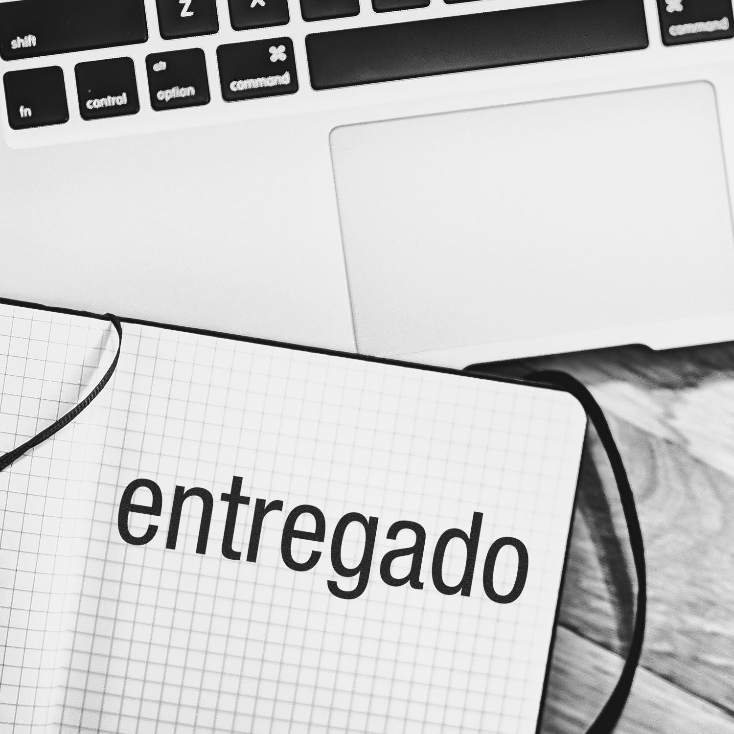 Self Inking Entregado Stamp marking entregado on a notebook, placed next to a laptop on a wooden desk.