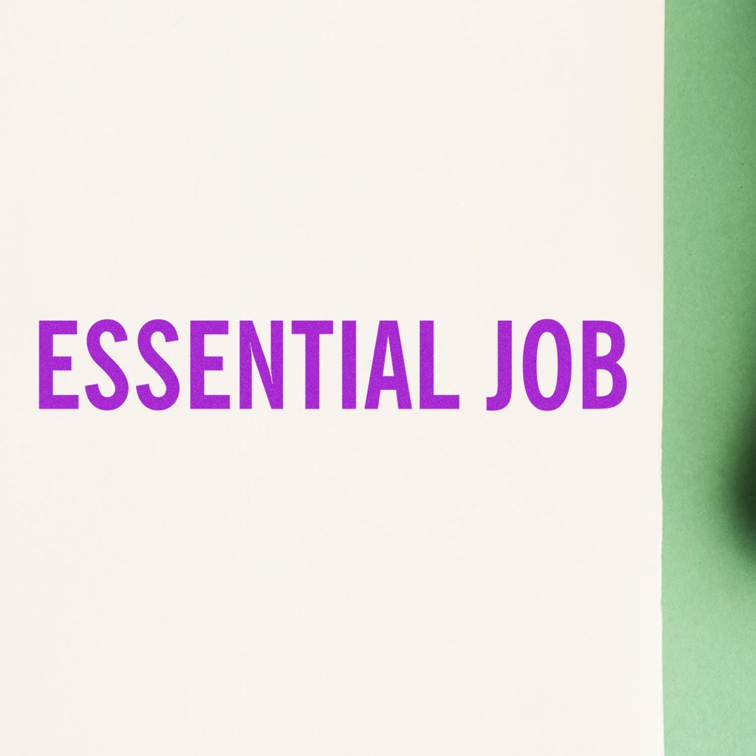 Slim Pre-Inked Essential Job Stamp used to imprint 'ESSENTIAL JOB' in bold purple letters on a white and green background.