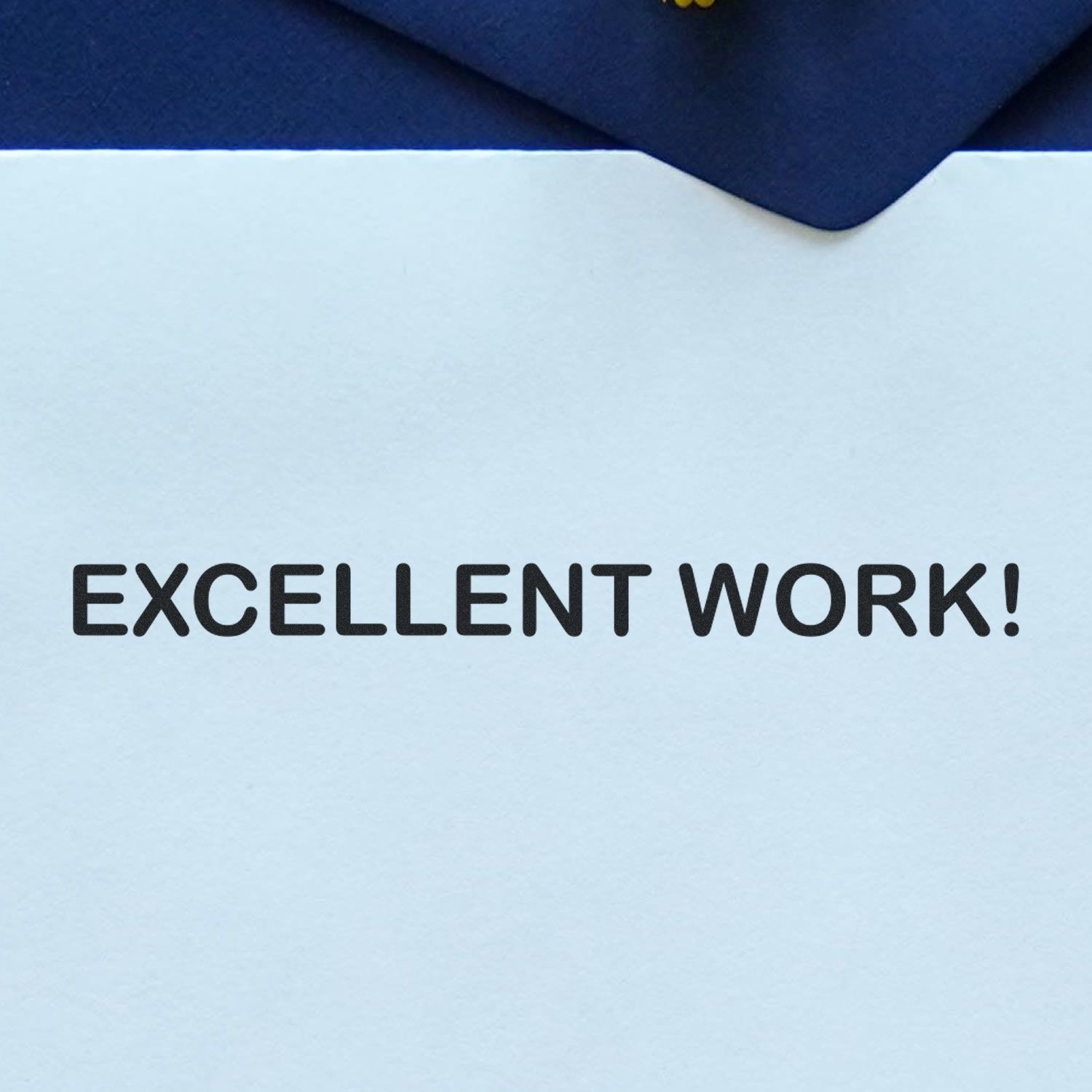 Paper stamped with 'EXCELLENT WORK!' using the Large Excellent Work Rubber Stamp, placed on a dark blue surface.