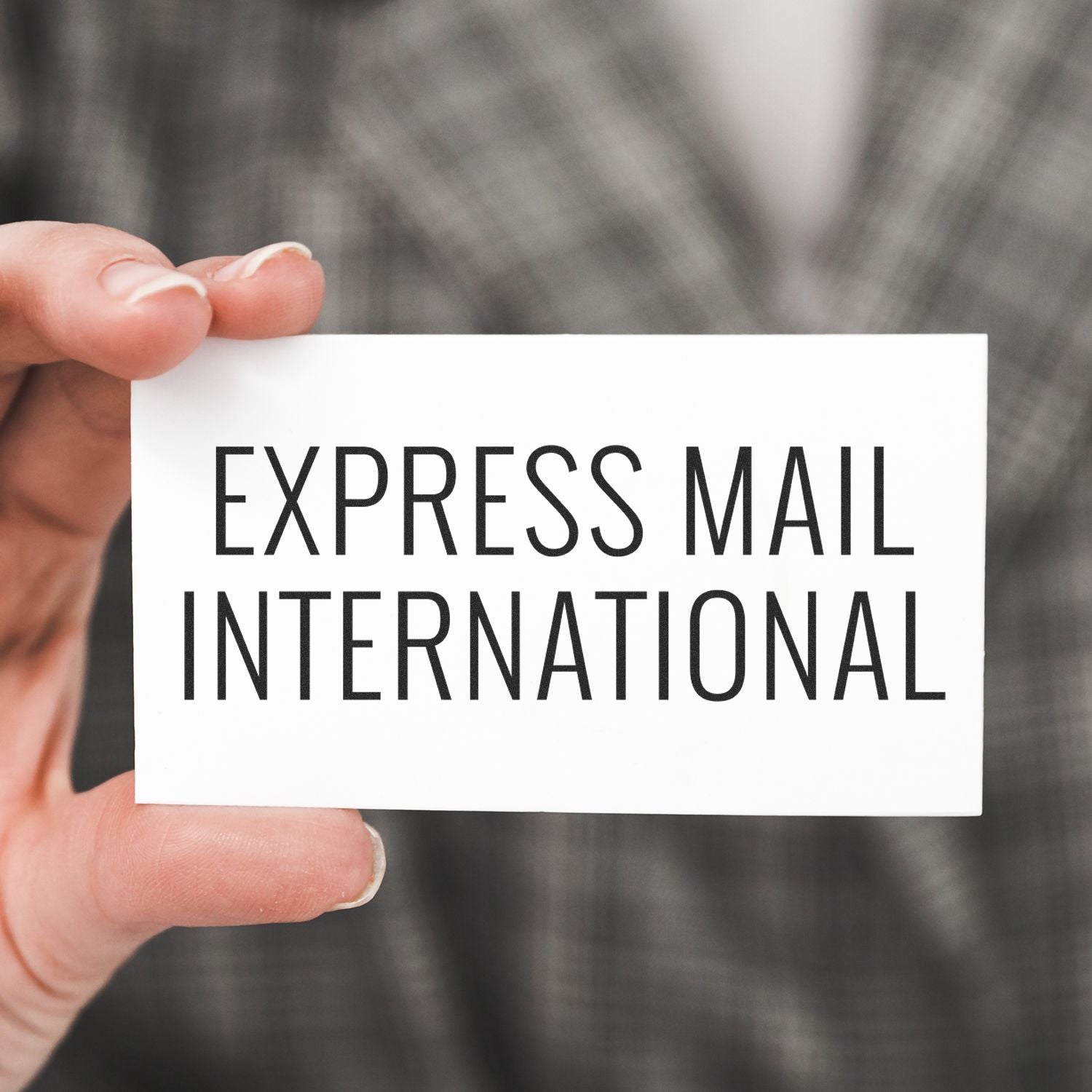 A hand holding a card with Express Mail International text, showcasing the Slim Pre-Inked Express Mail International Stamp.