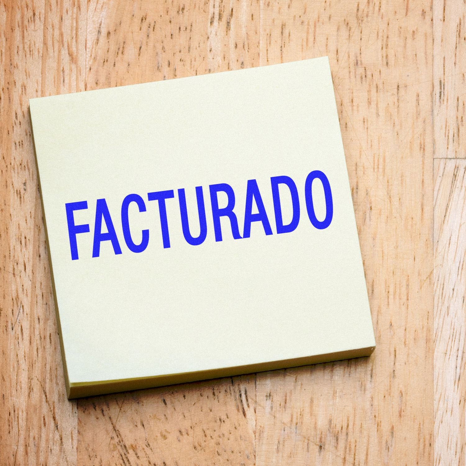 Large Self Inking Facturado Stamp in use, imprinting the word FACTURADO in blue ink on a light-colored paper on a wooden surface.