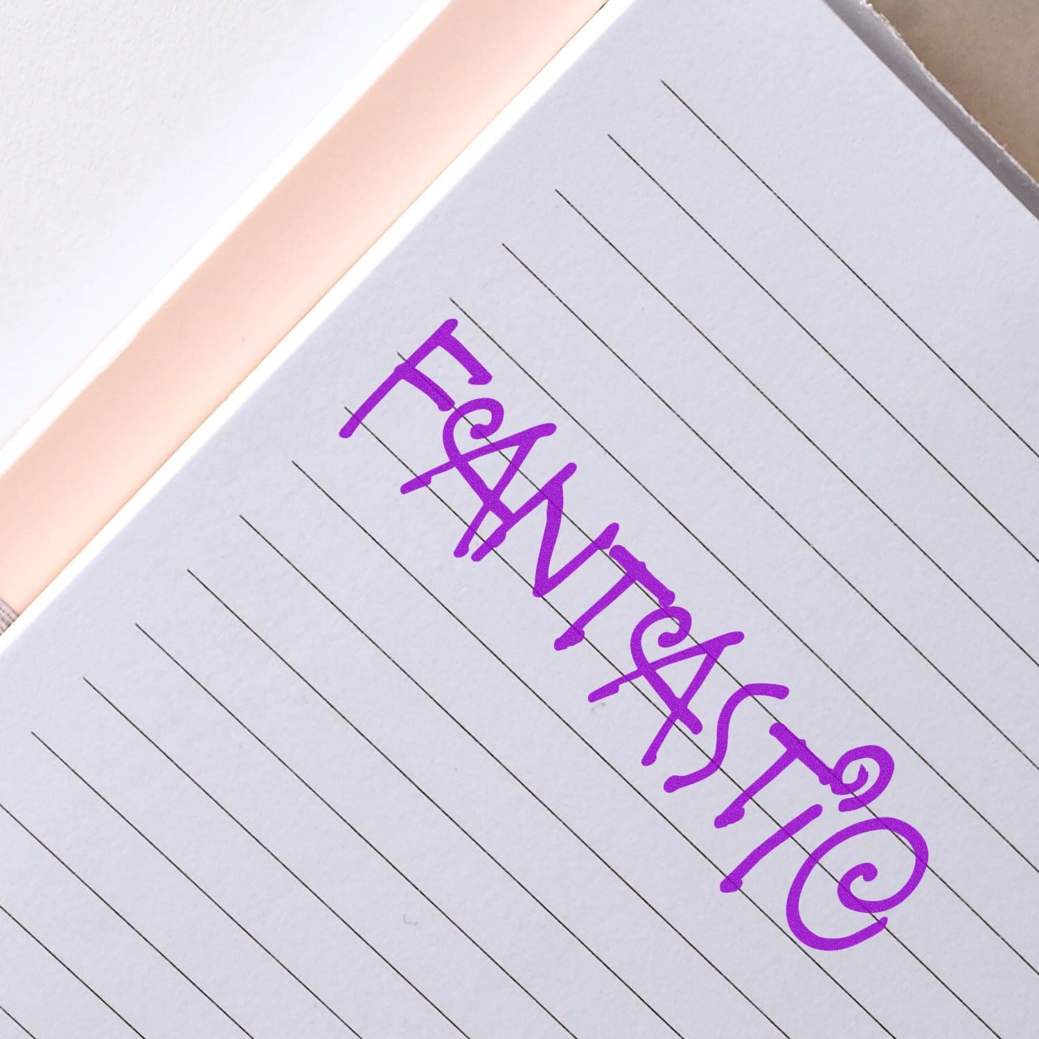 Large Pre-Inked Fantastic Stamp in use, creating a vibrant purple FANTASTIC imprint on a lined notebook page.