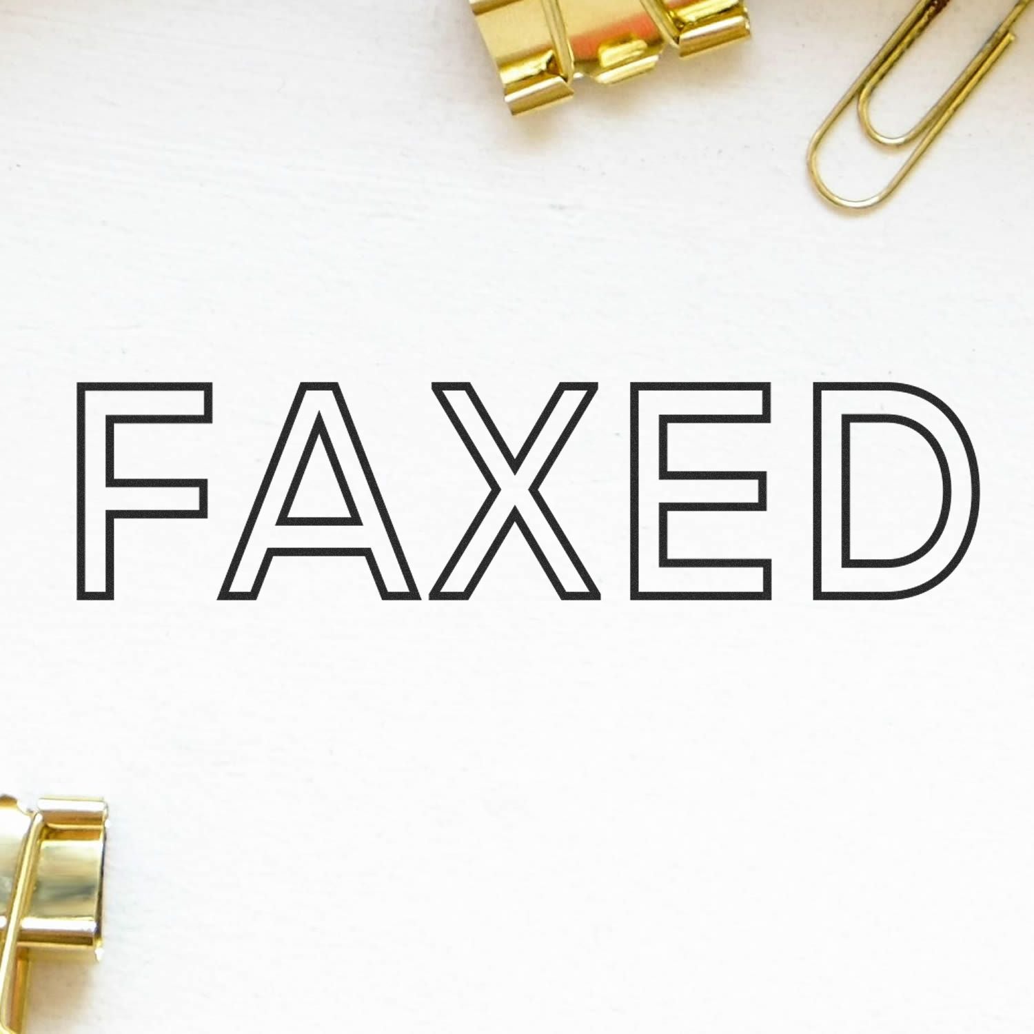 Large Self Inking Faxed Stamp marking the word FAXED on white paper, surrounded by gold paper clips and binder clips.