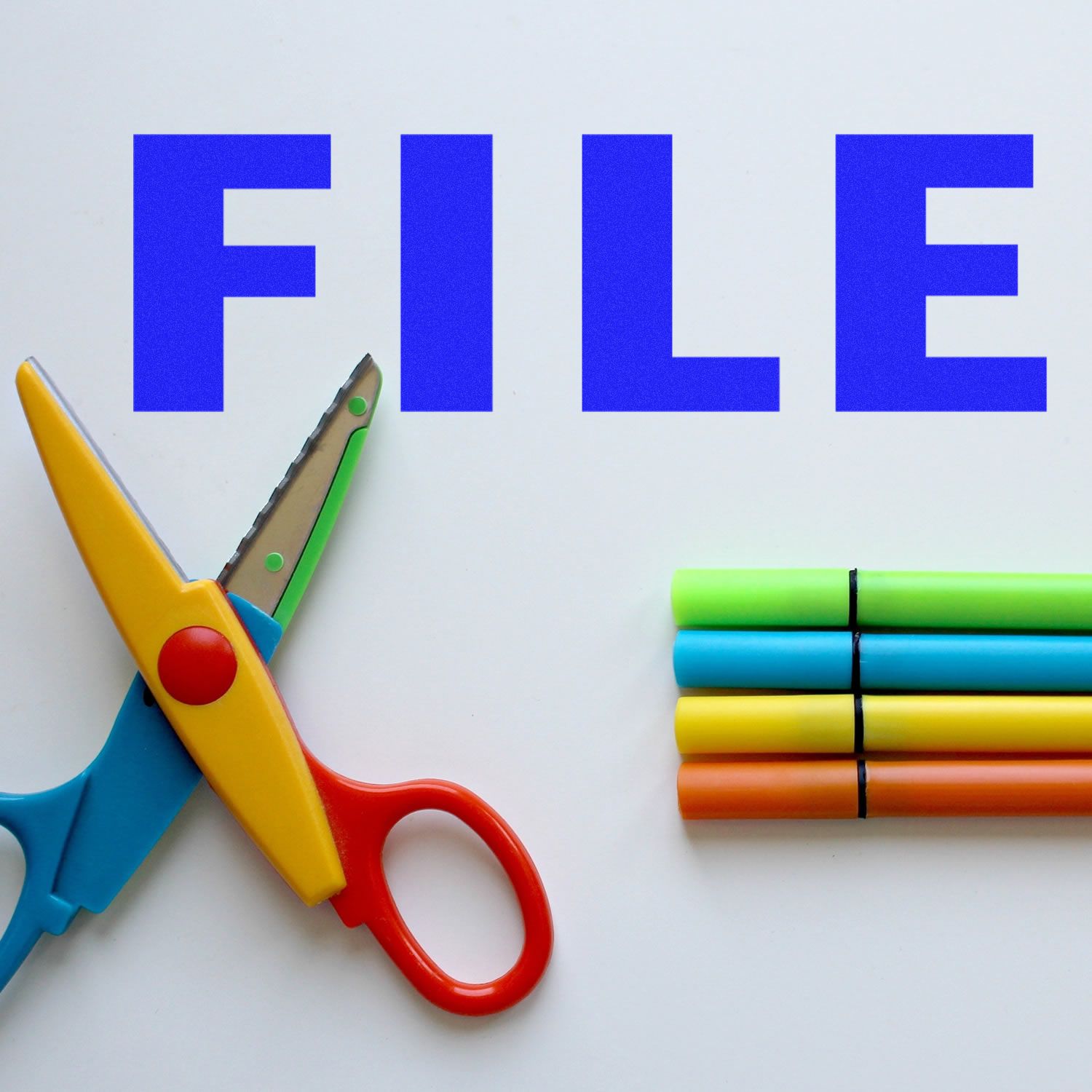 Colorful scissors and markers next to a blue FILE text, showcasing the Slim Pre-Inked File Stamp in use.