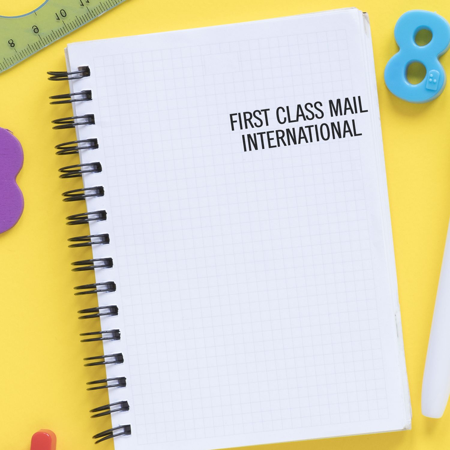 A notebook with First Class Mail International stamped on it using the First Class Mail International Rubber Stamp, surrounded by stationery.