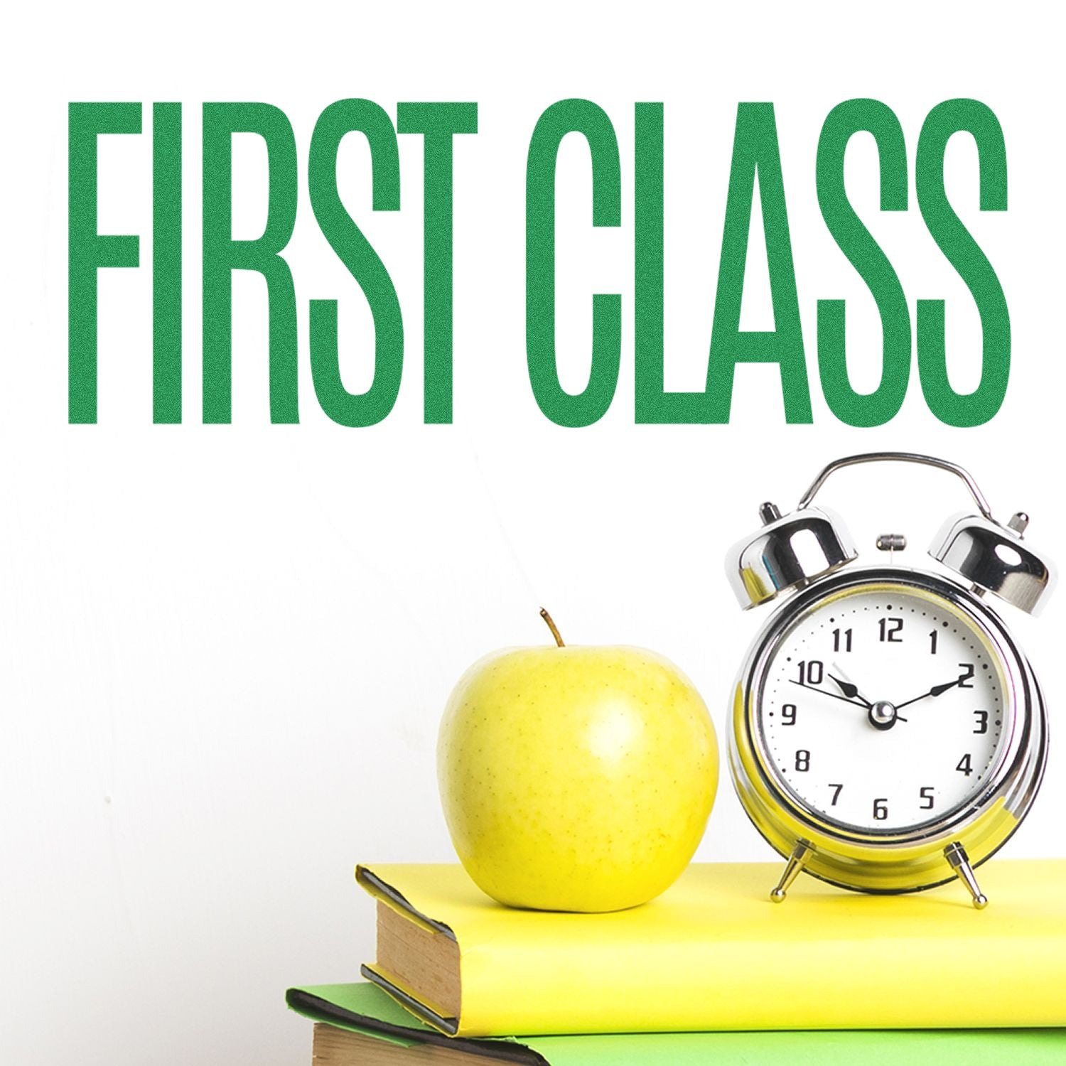 Self Inking First Class Stamp in use, displaying FIRST CLASS text in green above a stack of books, an apple, and an alarm clock.