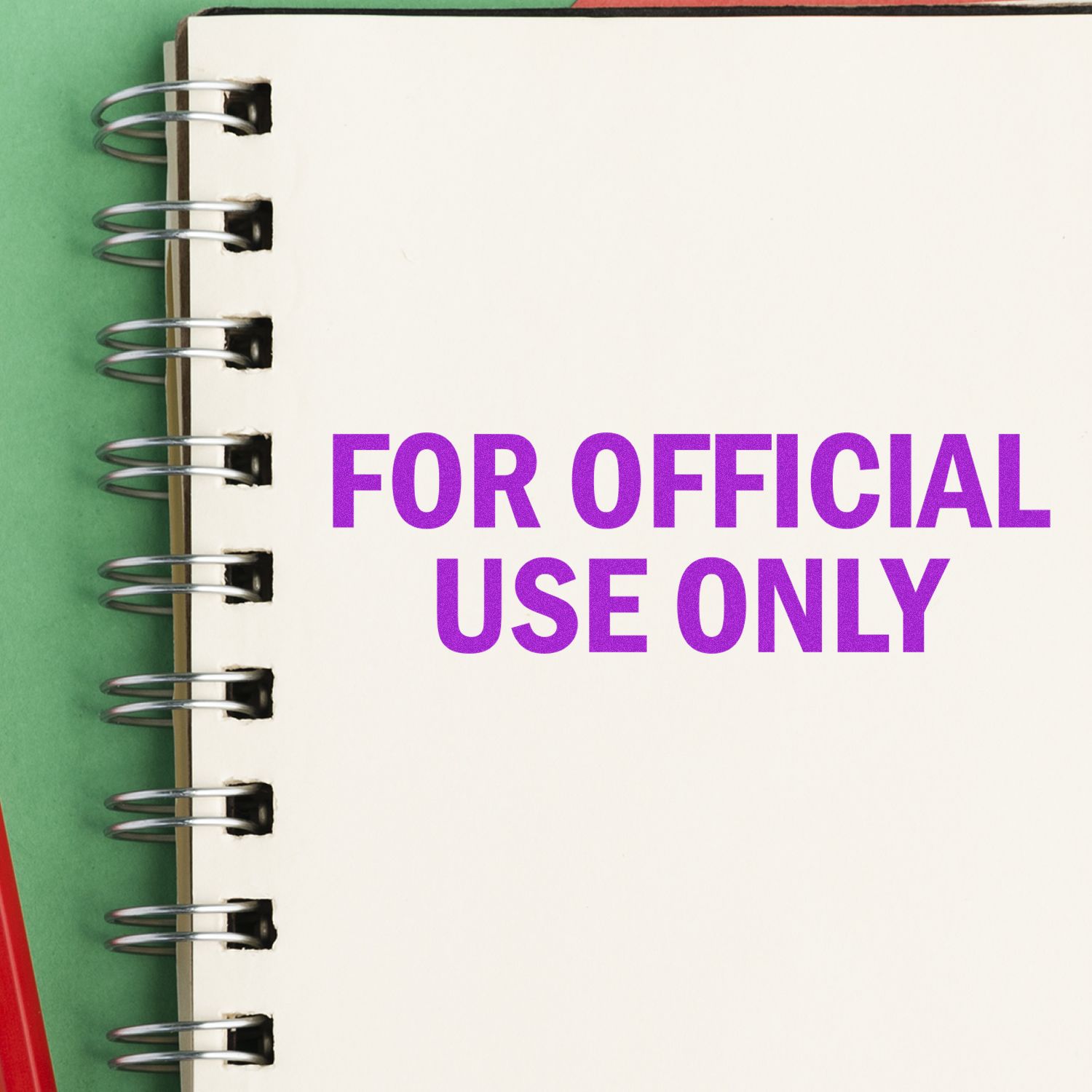 A notebook with FOR OFFICIAL USE ONLY stamped in purple using the For Official Use Only Rubber Stamp, placed on a green and red surface.