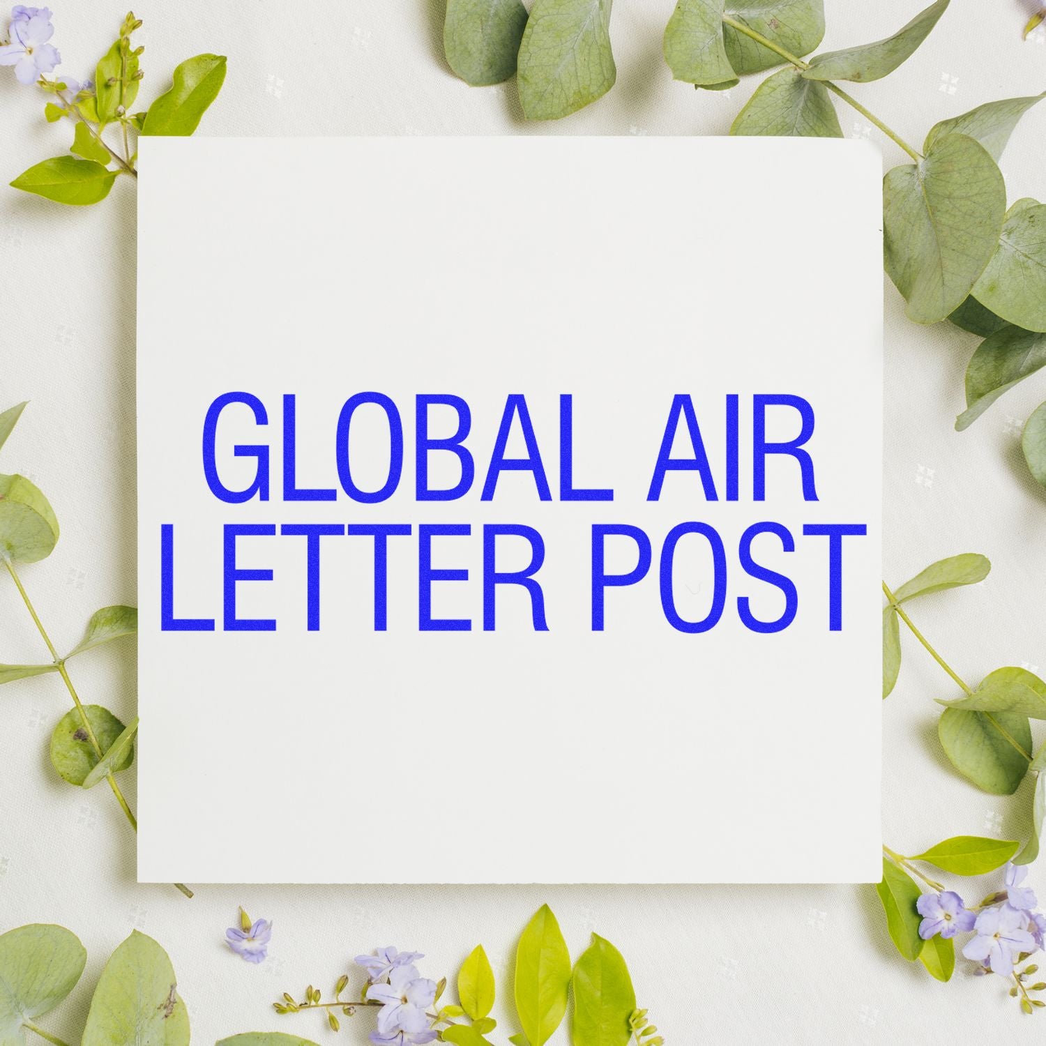 Large Global Air Letter Post Rubber Stamp in blue ink on white paper, surrounded by green leaves and small purple flowers.