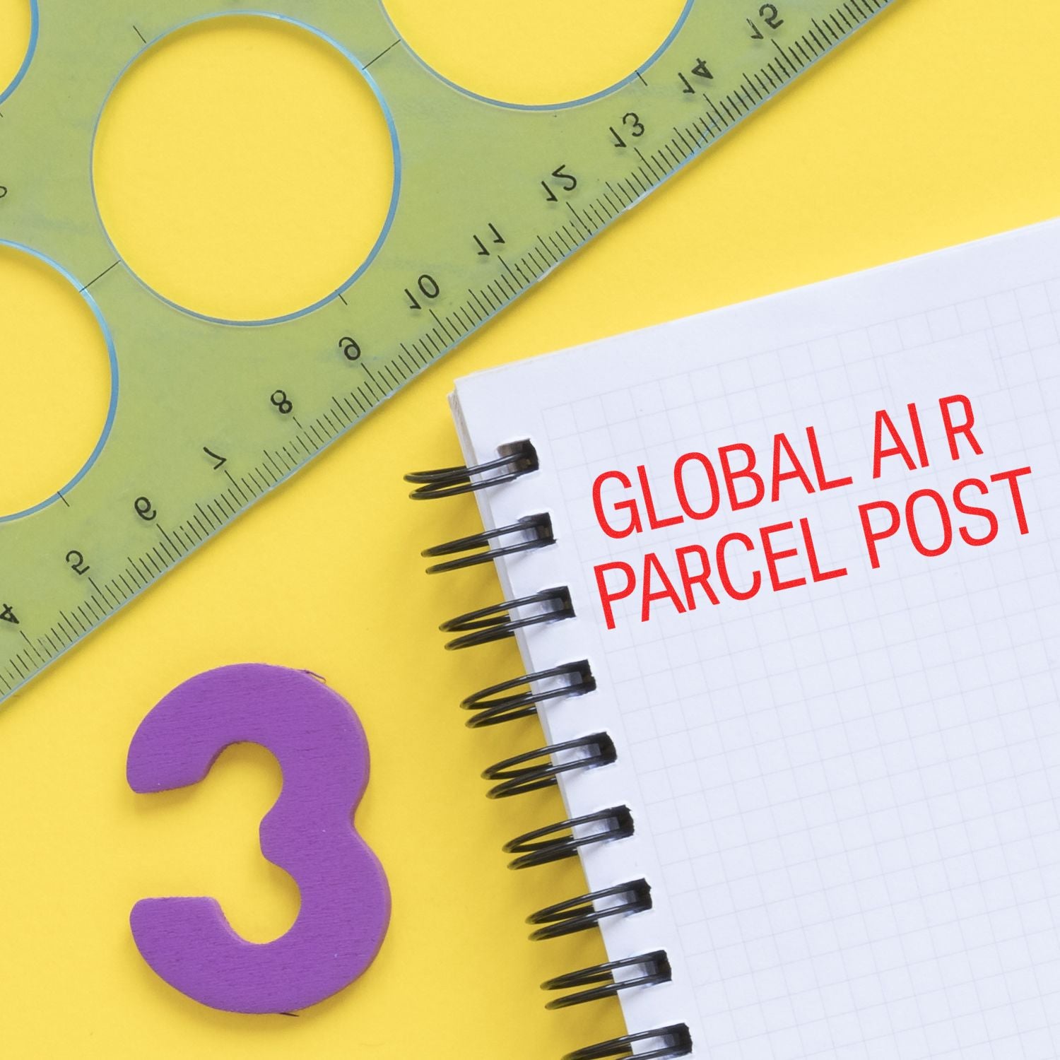 Global Air Parcel Post Rubber Stamp in red ink on a spiral notebook, with a green ruler and purple number 3 on a yellow background.