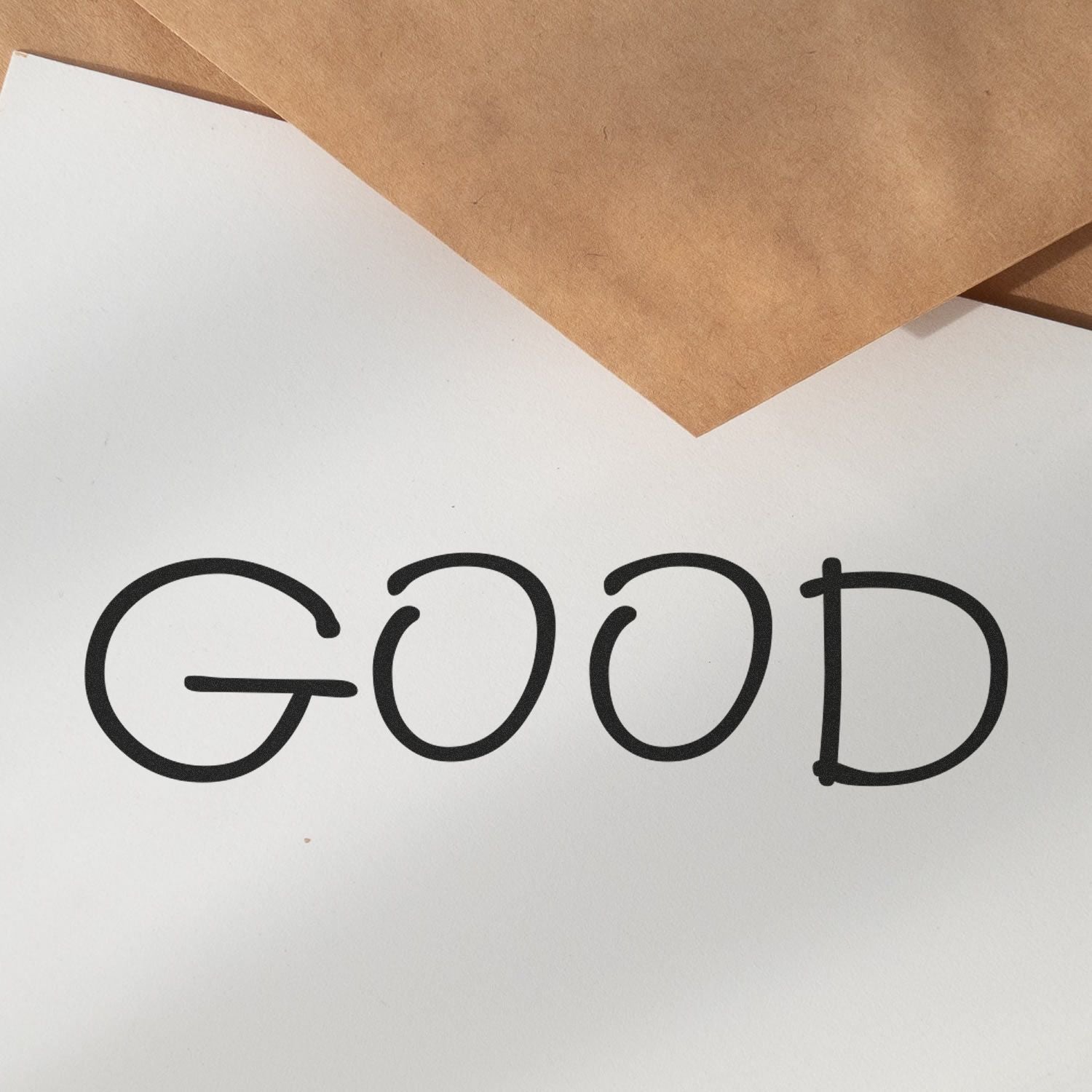 Large Pre-Inked Good Stamp imprinting the word GOOD in bold black letters on white paper, with brown envelopes in the background.