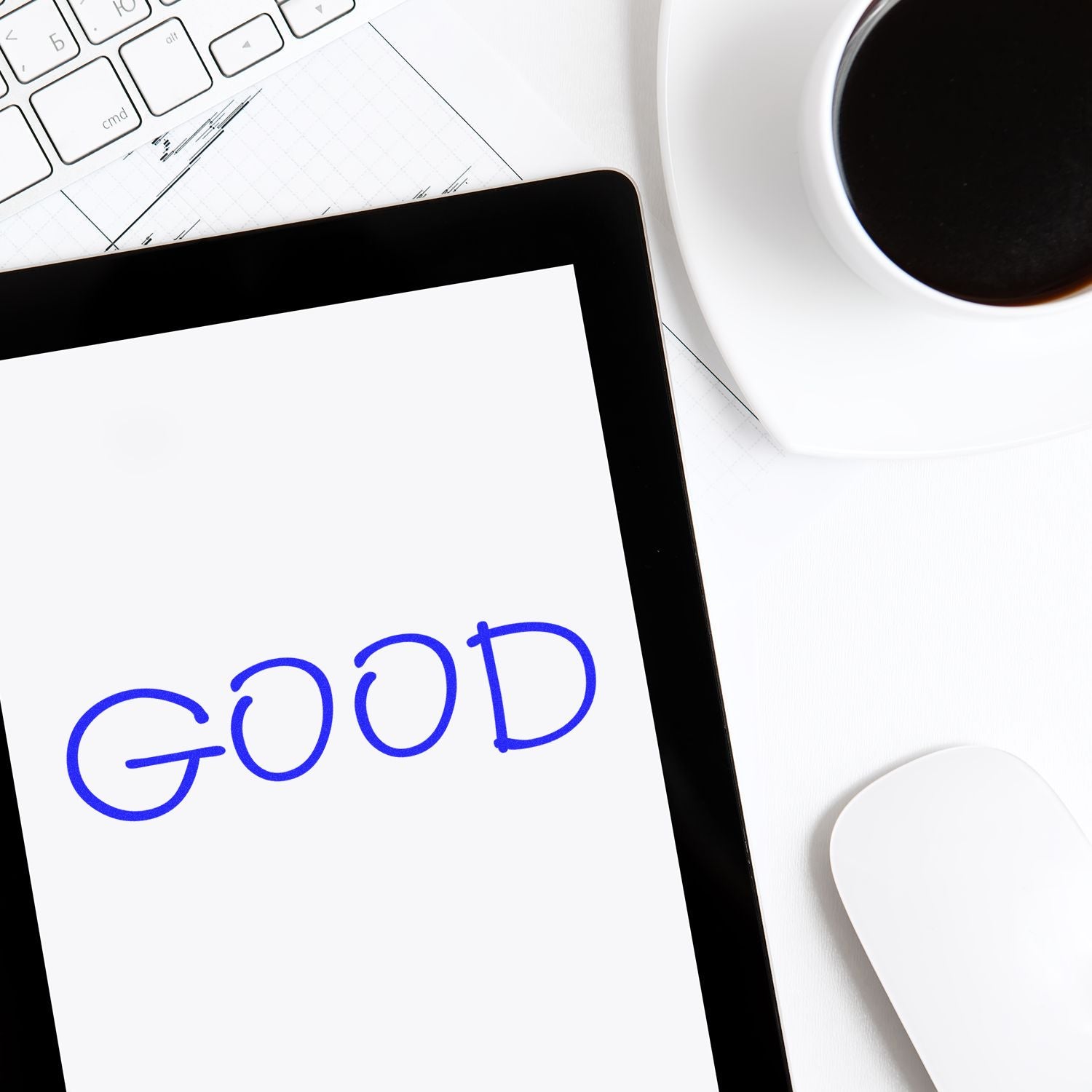 Large Good Rubber Stamp imprint on a white paper, placed on a tablet screen, with a keyboard, mouse, and coffee cup in the background.