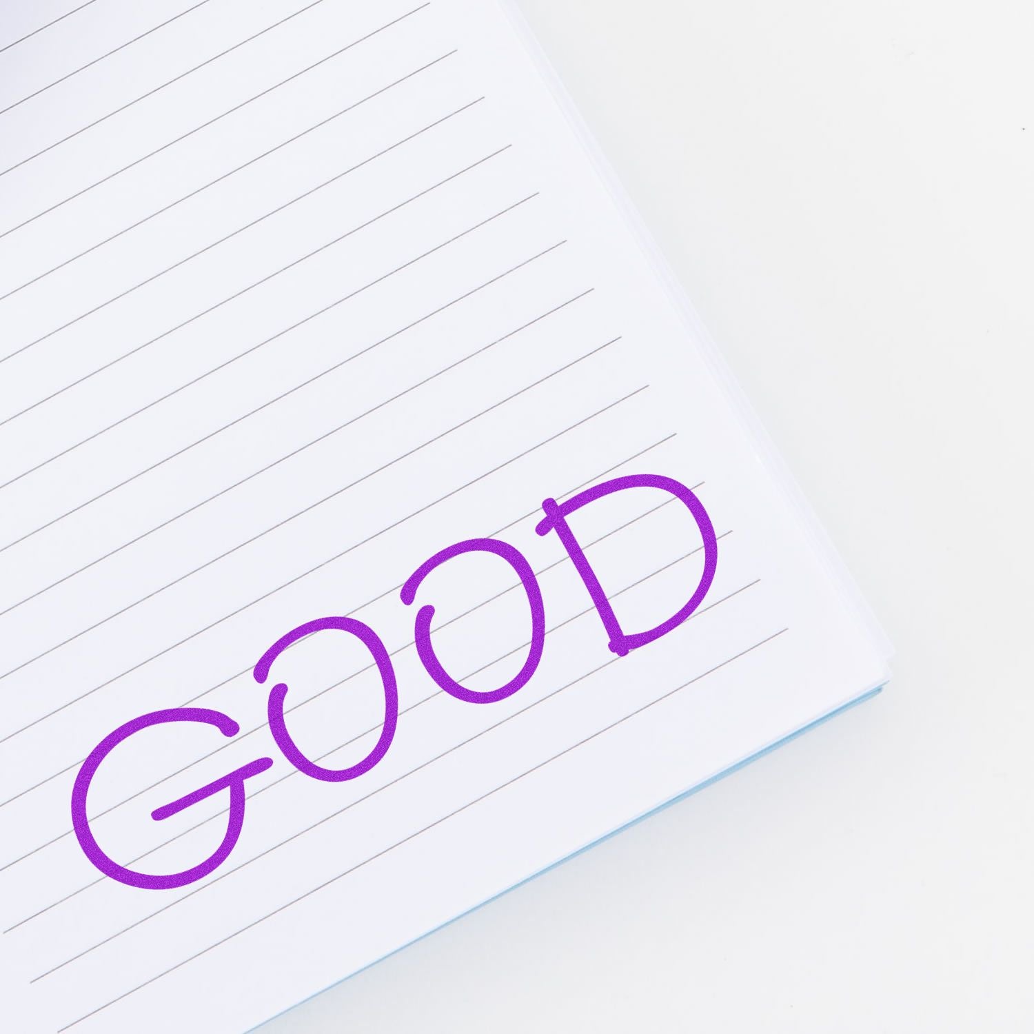 Notebook page stamped with the word 'GOOD' in purple ink using the Good Rubber Stamp, showing clear and bold lettering.