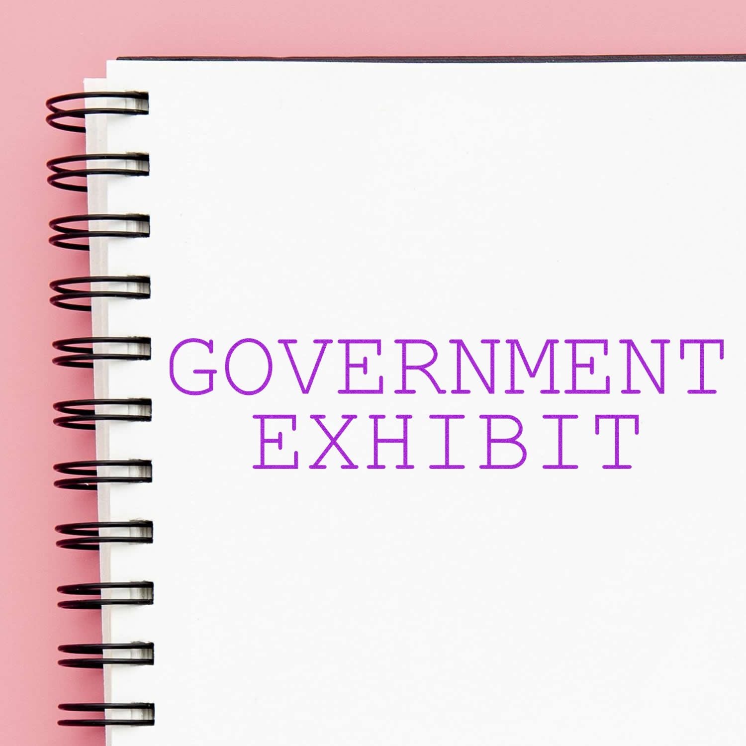 A notebook with a spiral binding and the words Government Exhibit stamped in purple ink using the Government Exhibit Rubber Stamp.