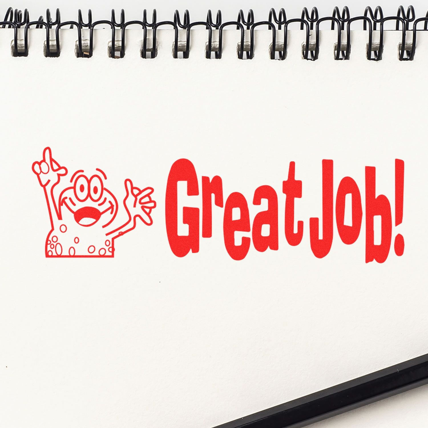 Self Inking Great Job Stamp imprint on a white notepad with a red cartoon character and the words Great Job! in bold red letters.