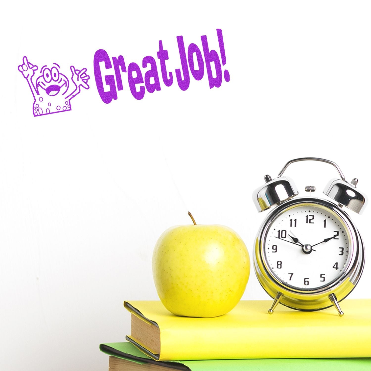 Large Great Job Rubber Stamp in purple ink on a white wall, next to a stack of books, a yellow apple, and a silver alarm clock.