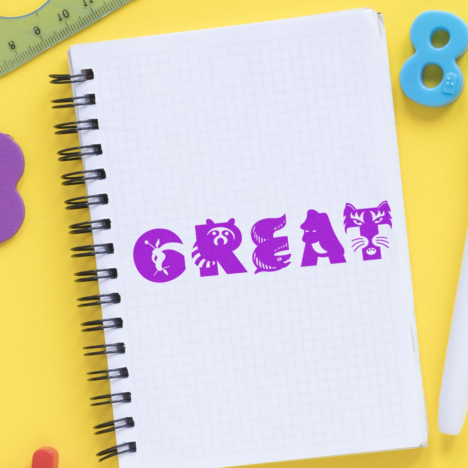 Notebook with purple animal-themed letters spelling 'CREAM' stamped using the Great Rubber Stamp, surrounded by colorful stationery.