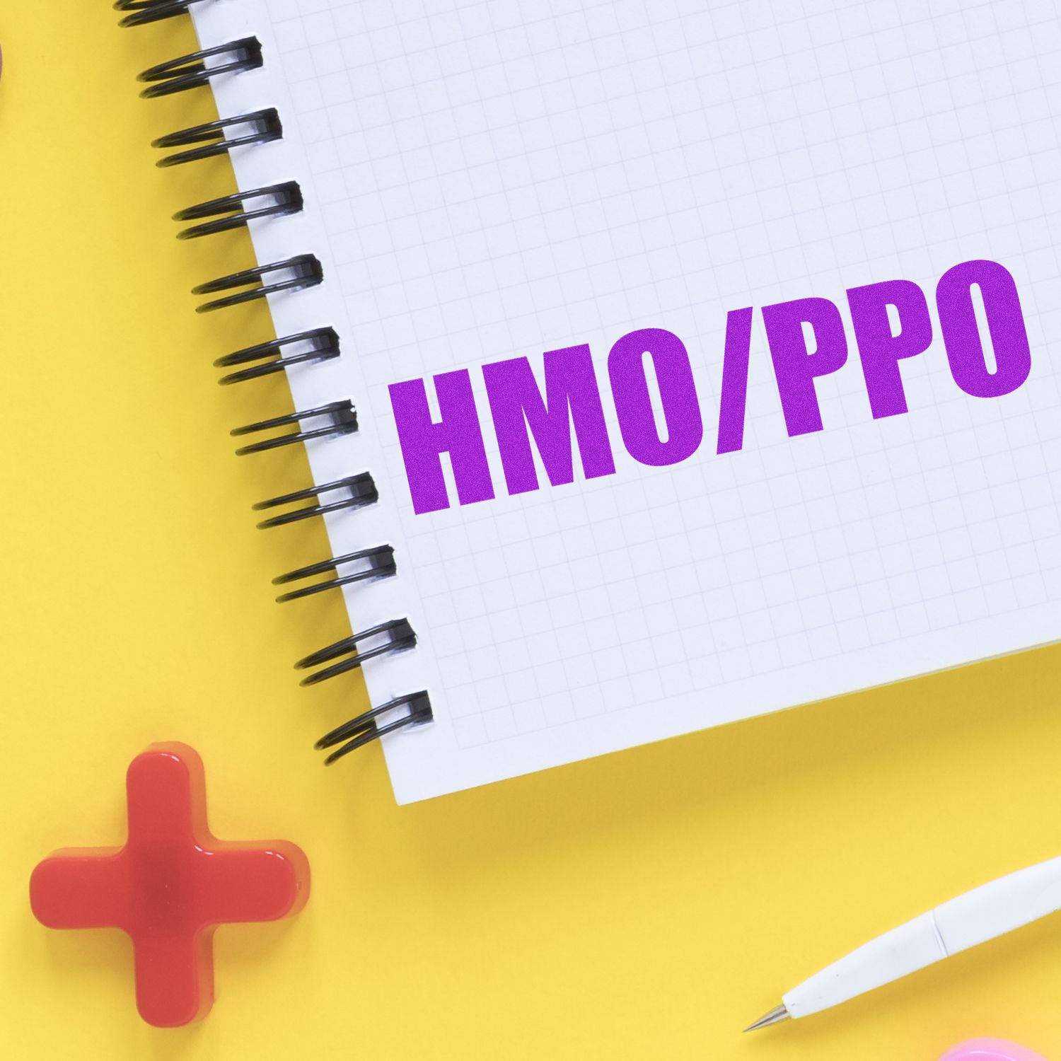 Large Self Inking HMO/PPO Stamp in use on a spiral notebook with a yellow background, red cross, and white pen nearby.