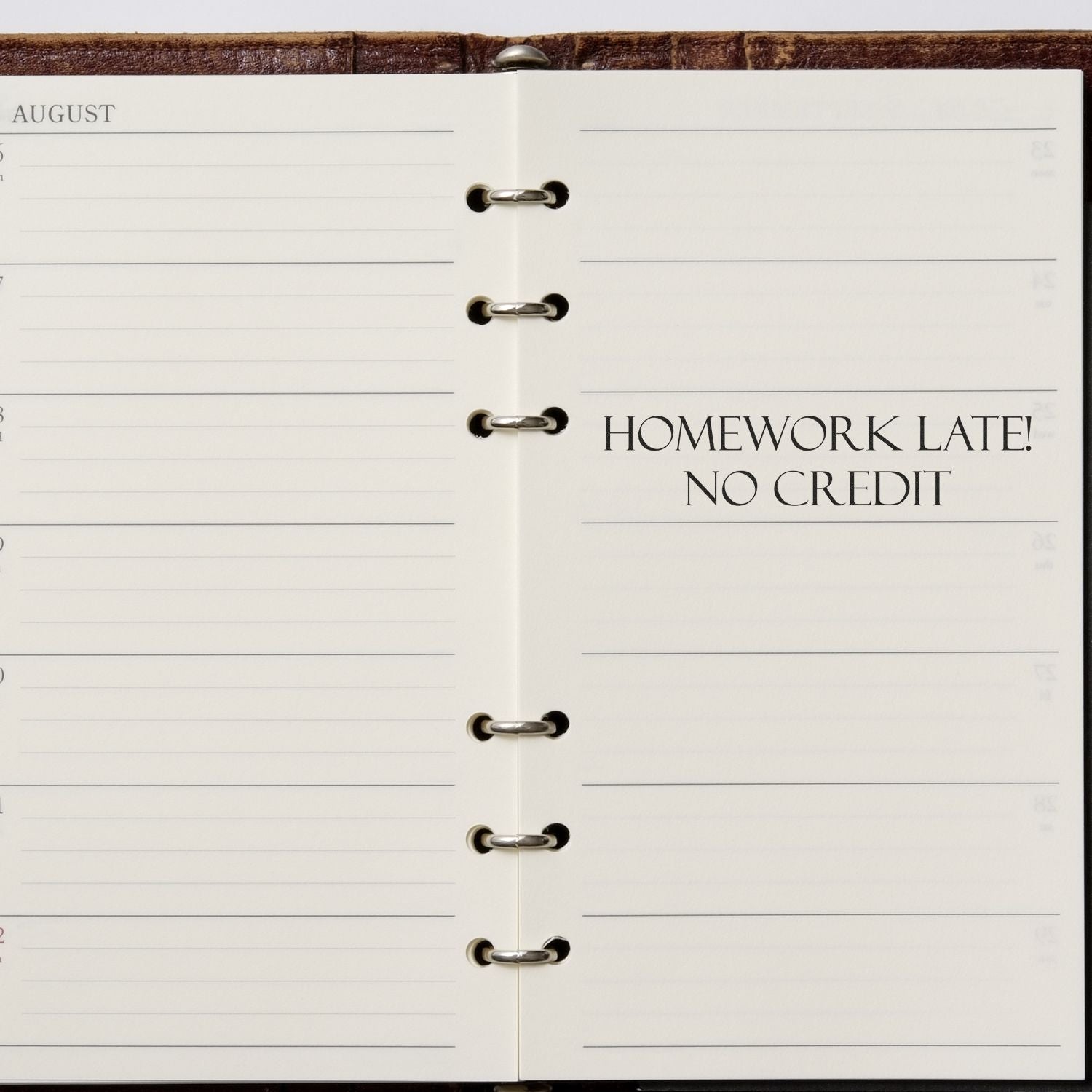 Open planner with HOMEWORK LATE! NO CREDIT stamped in black ink using the Large Self Inking Homework Late No Credit Stamp.