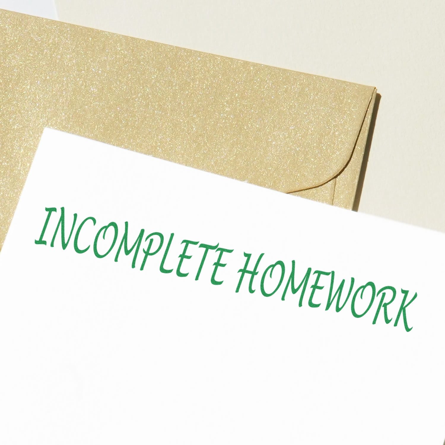 A paper stamped with INCOMPLETE HOMEWORK using the Self Inking Incomplete Homework Stamp, placed on a glittery gold envelope.