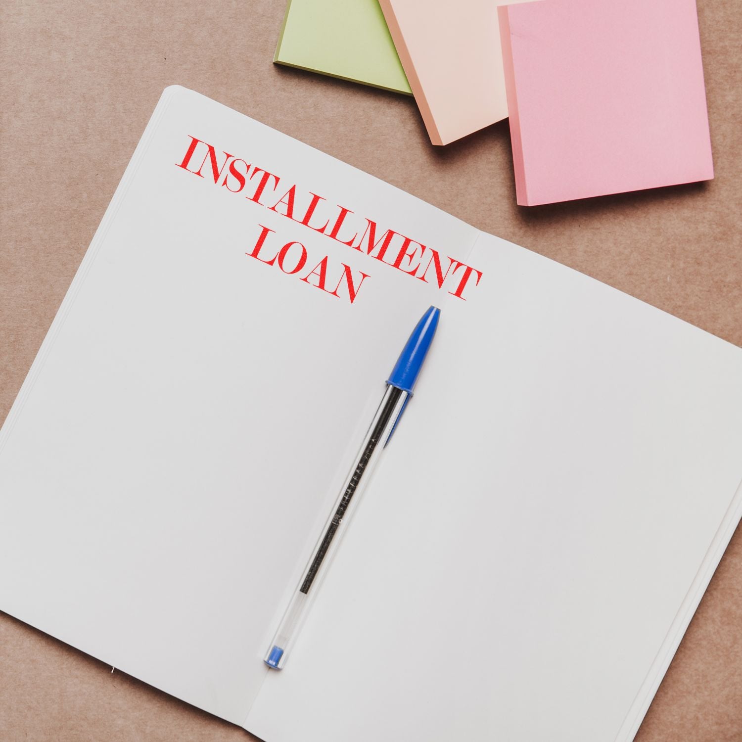 Open notebook with Installment Loan stamped in red, blue pen, and colorful sticky notes in the background. Installment Loan Rubber Stamp in use.