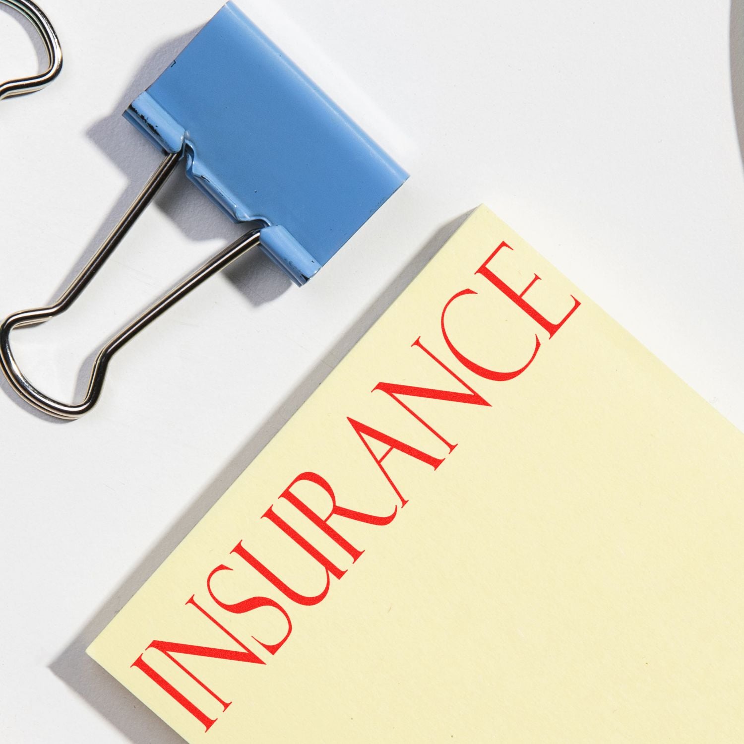 A Large Pre-Inked Insurance Stamp marks a document with the word "INSURANCE" in red, next to a blue binder clip on a white surface.