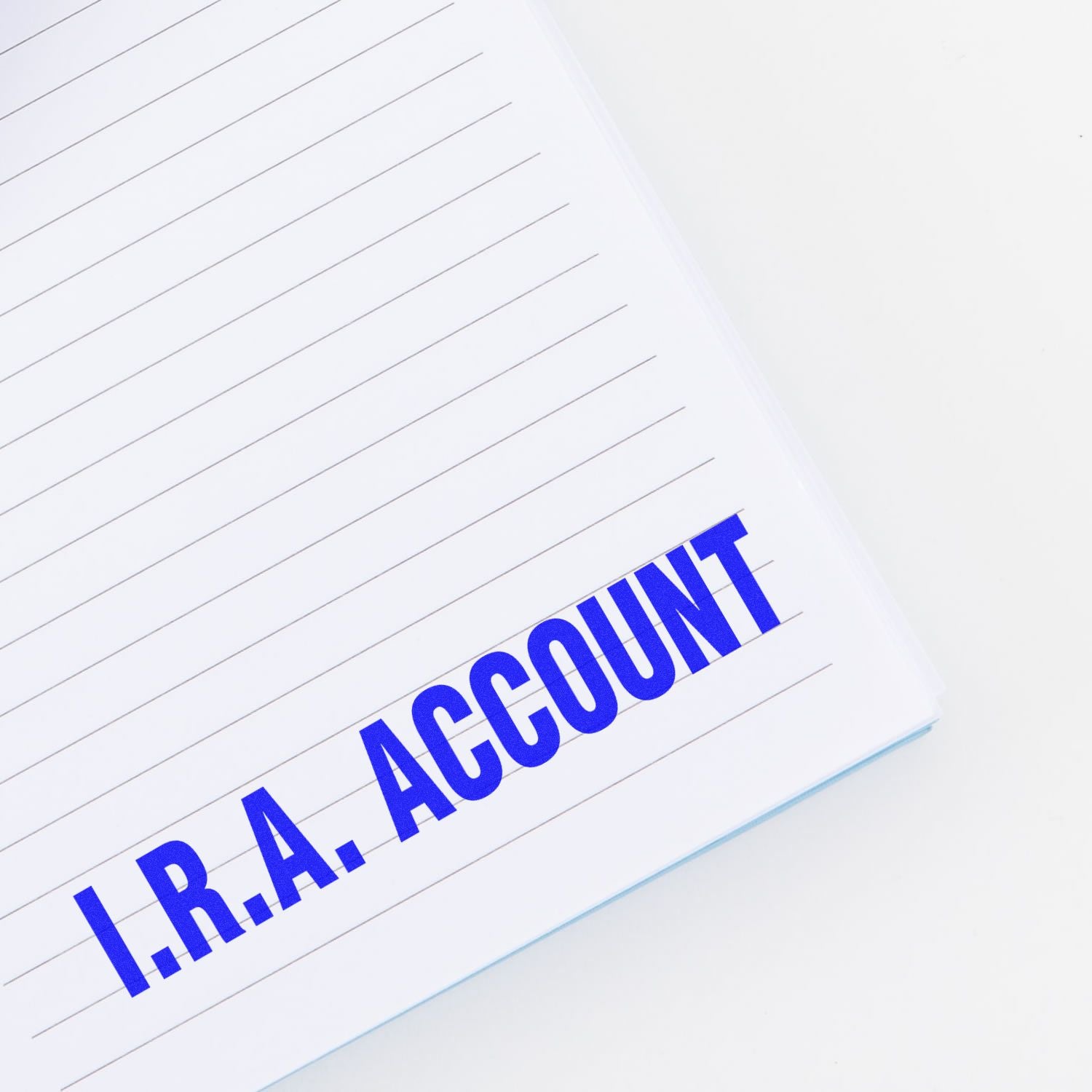 Large I.R.A. Account Rubber Stamp used on a lined notebook page, displaying the text "I.R.A. ACCOUNT" in bold blue letters.