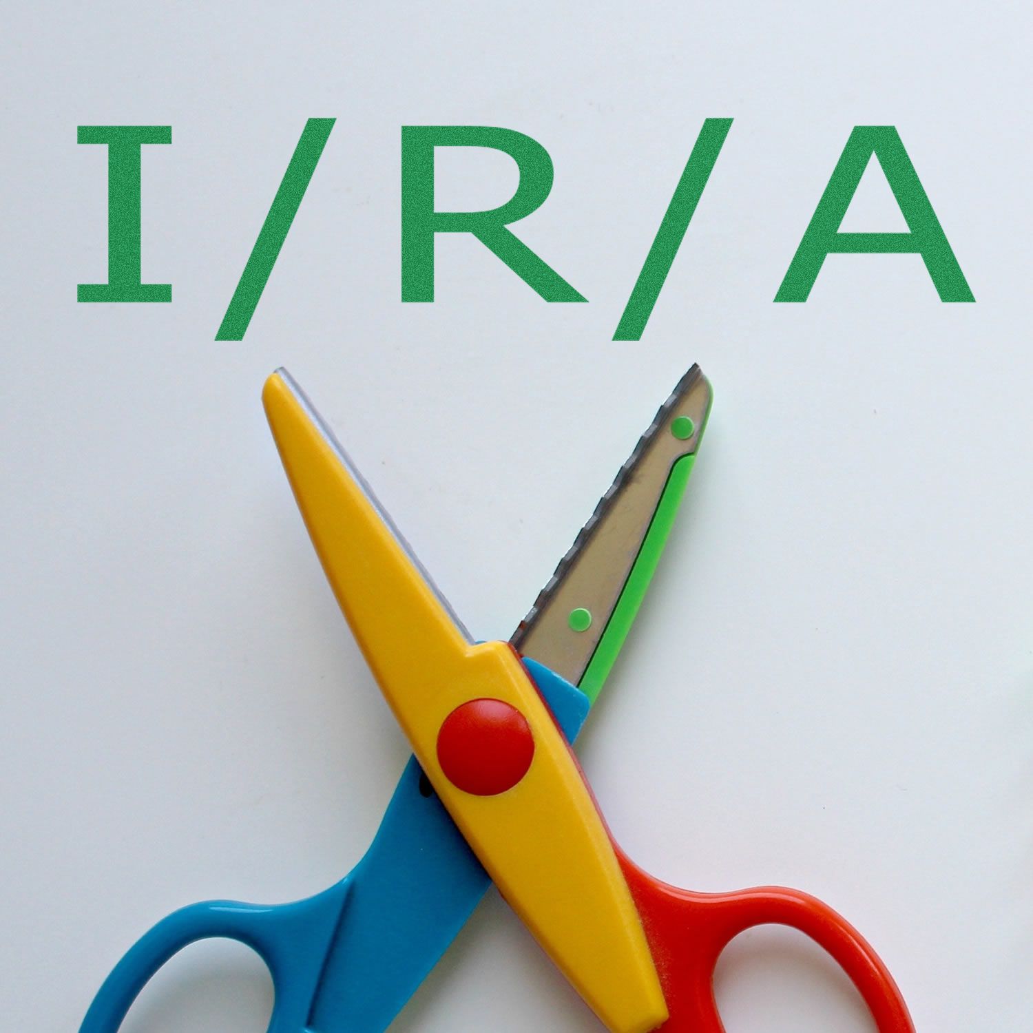 Large Pre-Inked I/R/A Stamp in use, with colorful scissors placed below the stamped letters I/R/A on a white background.