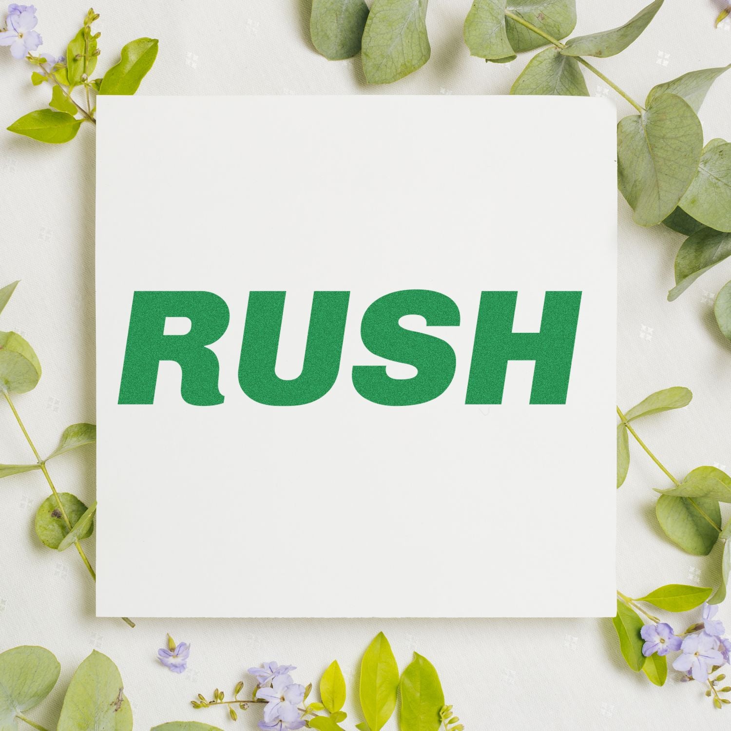 Green 'RUSH' text stamped on white paper surrounded by green leaves using a Slim Pre-Inked Italic Rush Stamp.