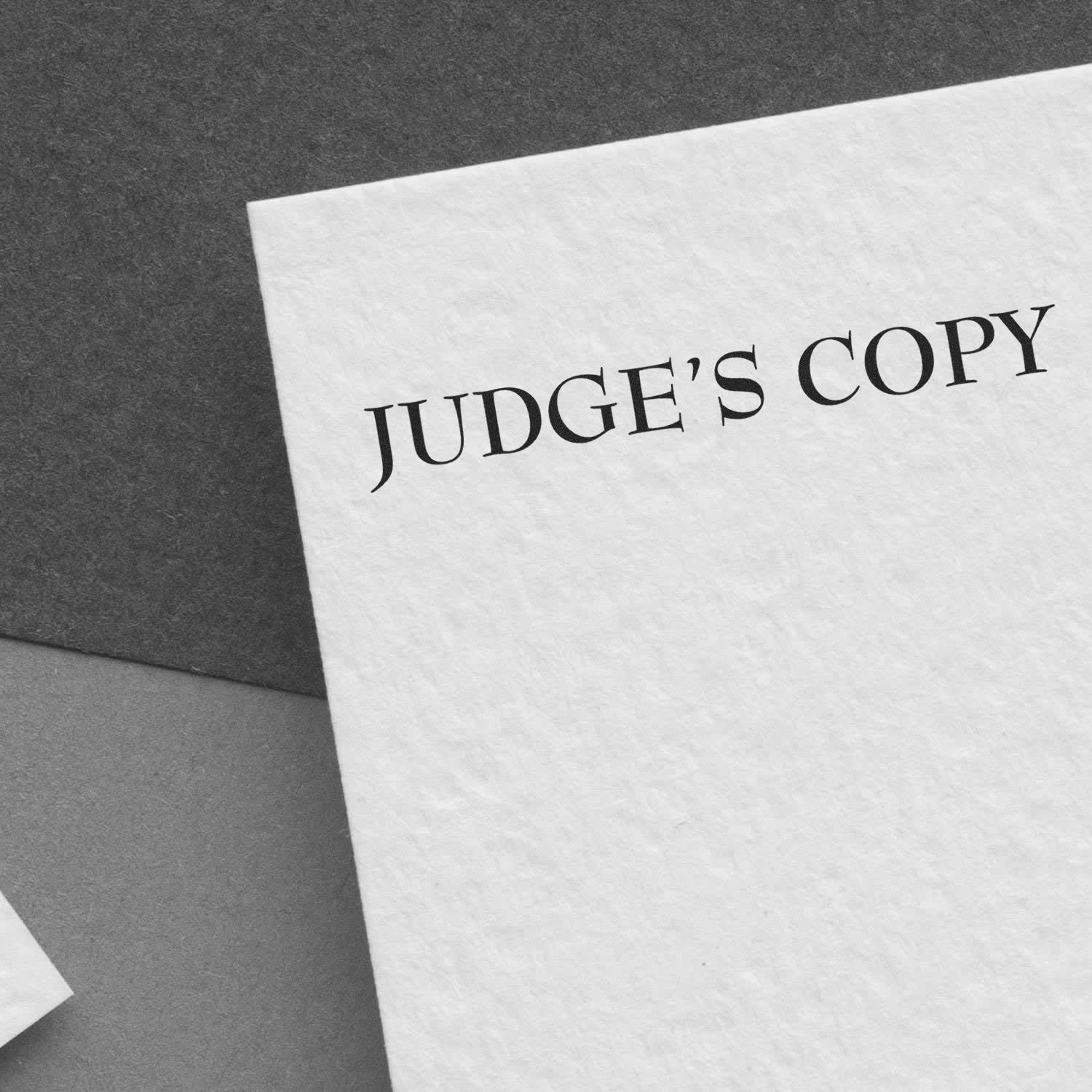 Close-up of a document stamped with 'JUDGE'S COPY' using the Judges Copy Legal Rubber Stamp, placed on a gray surface.