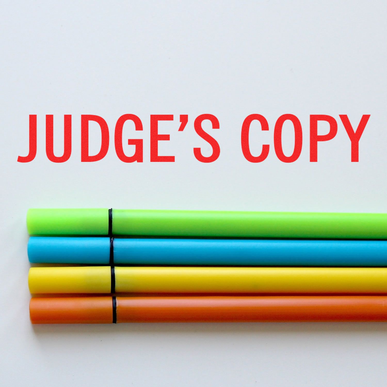 Large Self Inking Judge's Copy Stamp in red ink on white paper, with four colorful markers below the stamped text.