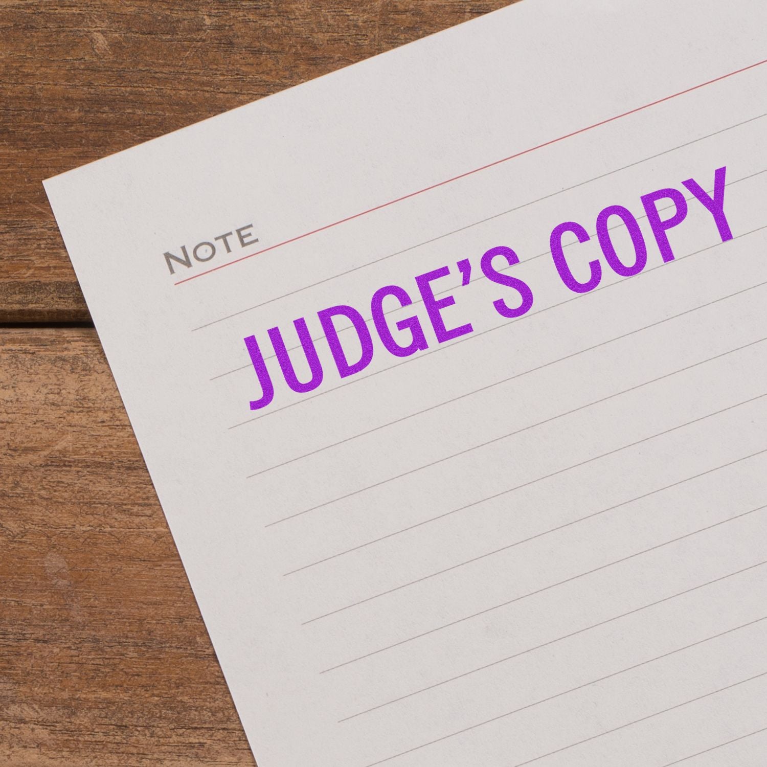 Large Judge's Copy Rubber Stamp in purple ink on a lined paper note, placed on a wooden surface.