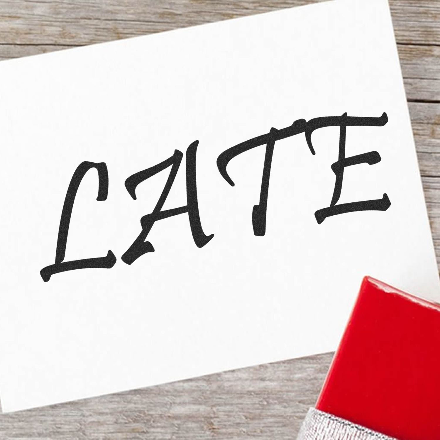 A red late rubber stamp on a white card with the word 'LATE' stamped in bold black letters, placed on a wooden surface.