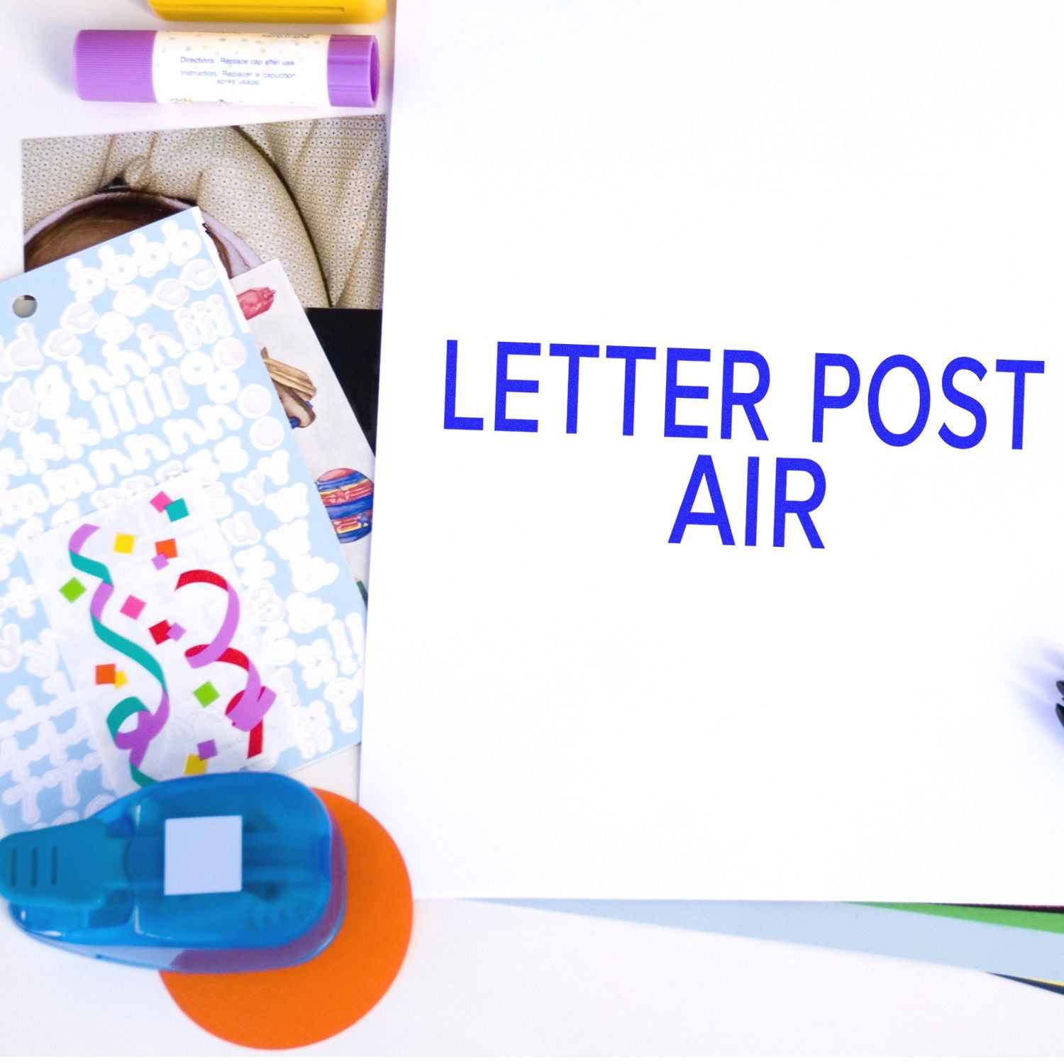 Slim Pre-Inked Letter Post Air Stamp in use on a white sheet with blue text, surrounded by colorful stationery items.