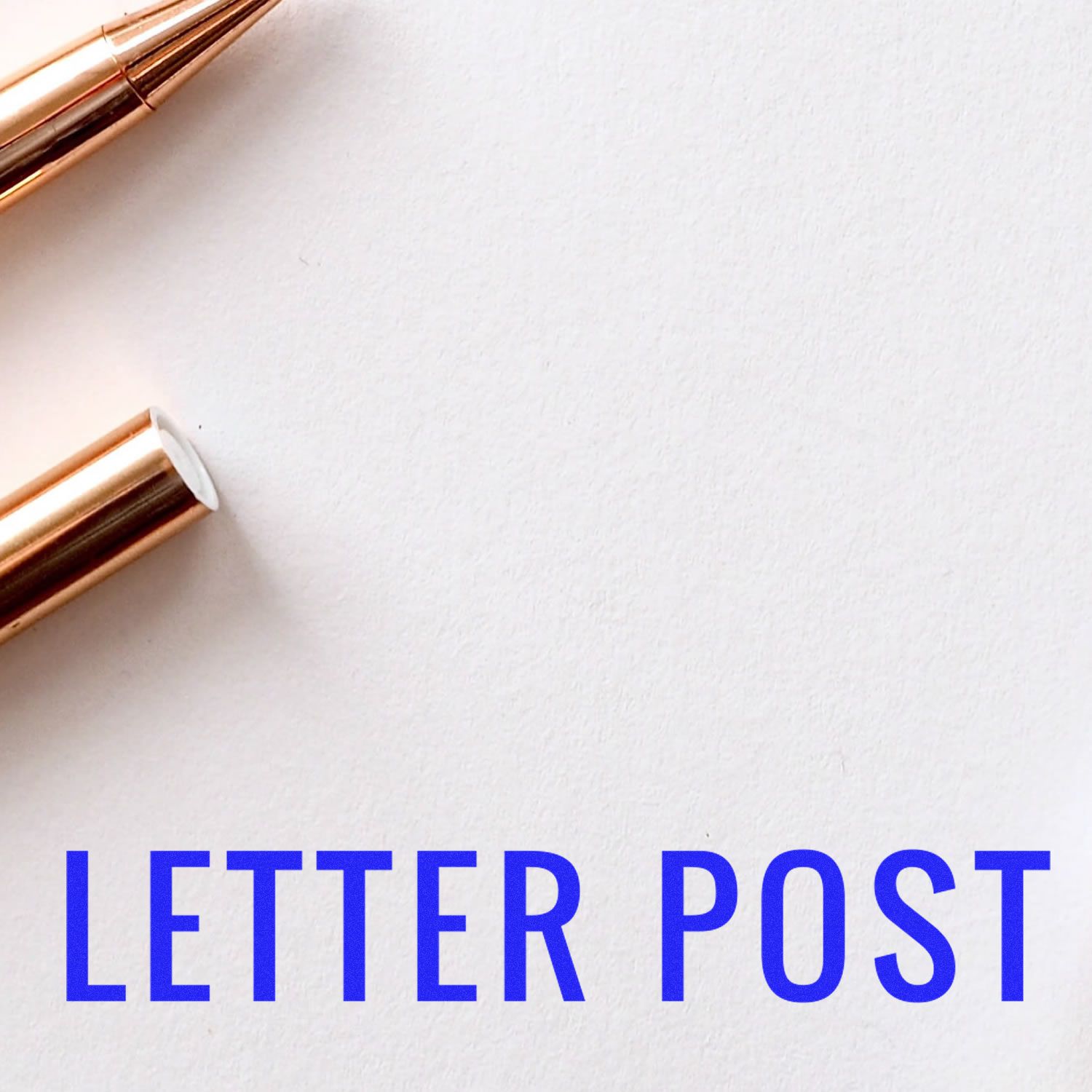 Self Inking Letter Post Stamp in use, with a close-up of the stamped text LETTER POST in blue on white paper, next to a gold pen.